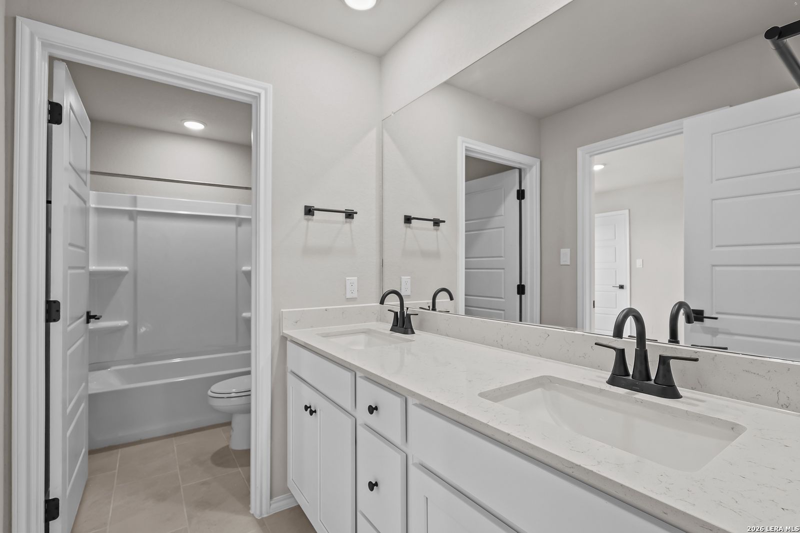 Dual vanity bathroom with white cabinetry, quartz countertops, and black faucets in Davidson Homes Sequoia C, San Antonio