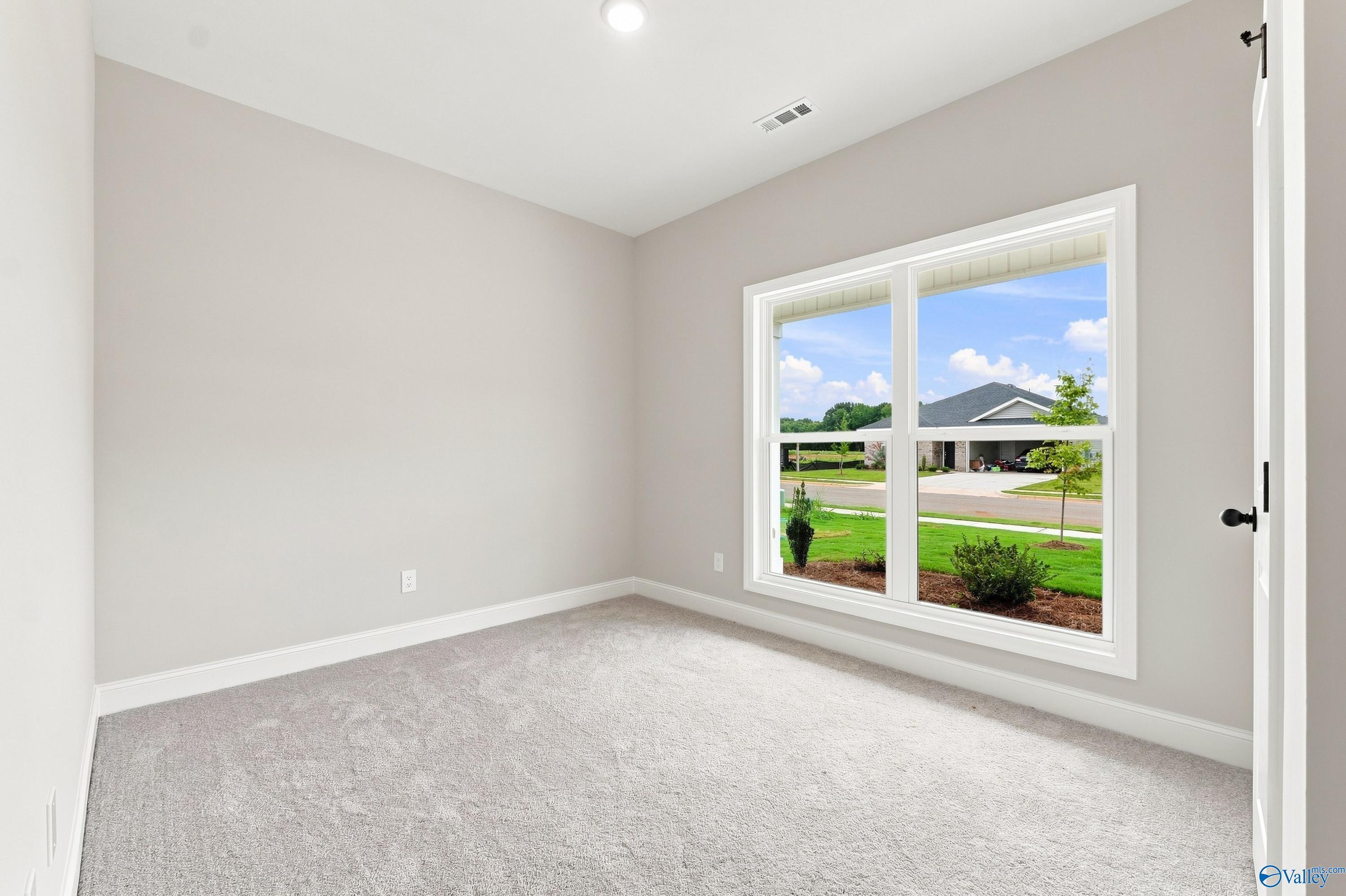 Bright, carpeted bedroom with large windows in The Asheville E floor plan at Forest Glen, Hazel Green, Alabama.