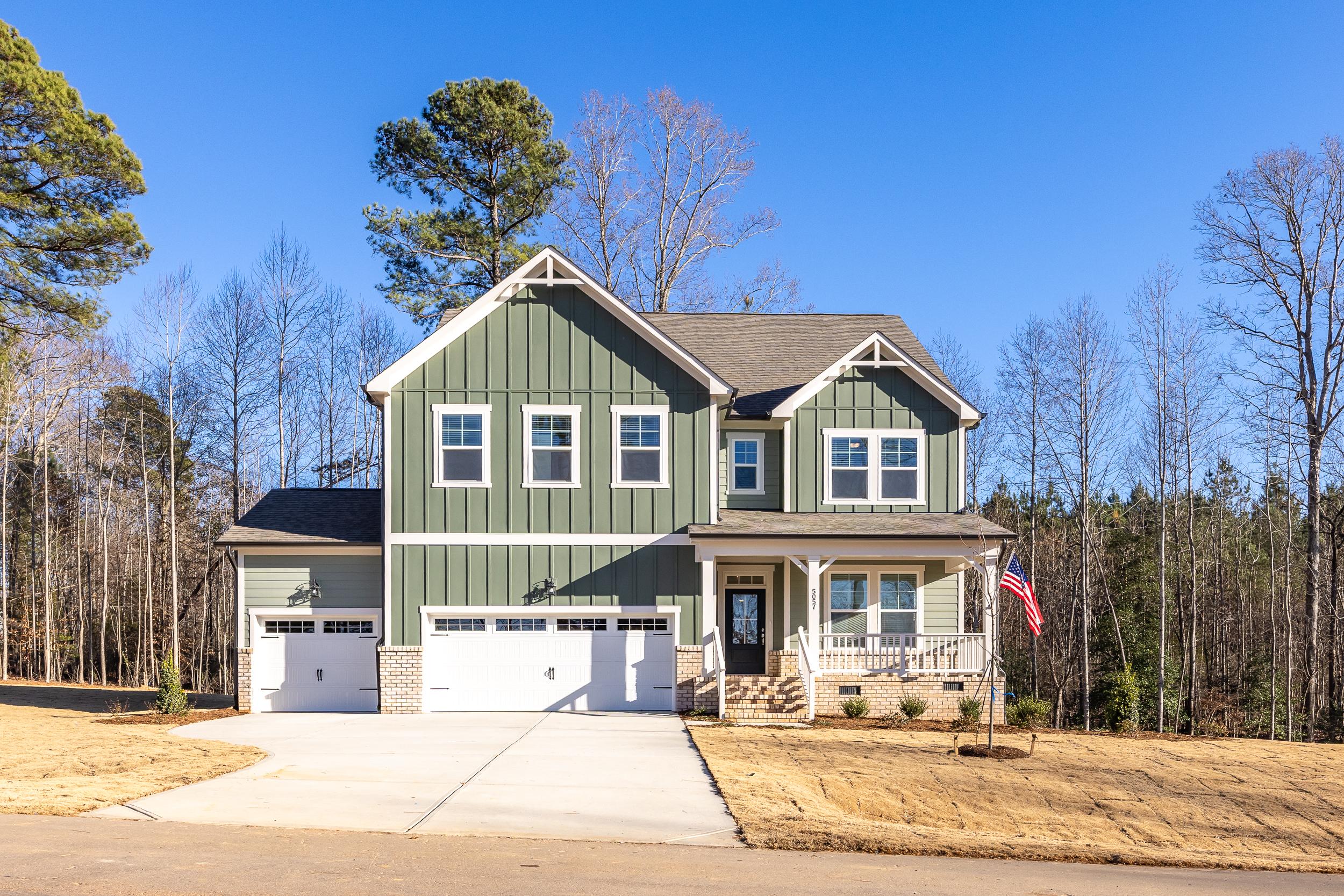 Green craftsman-style home by Davidson Homes at Rockport in Wake Forest, North Carolina with a three-car garage.