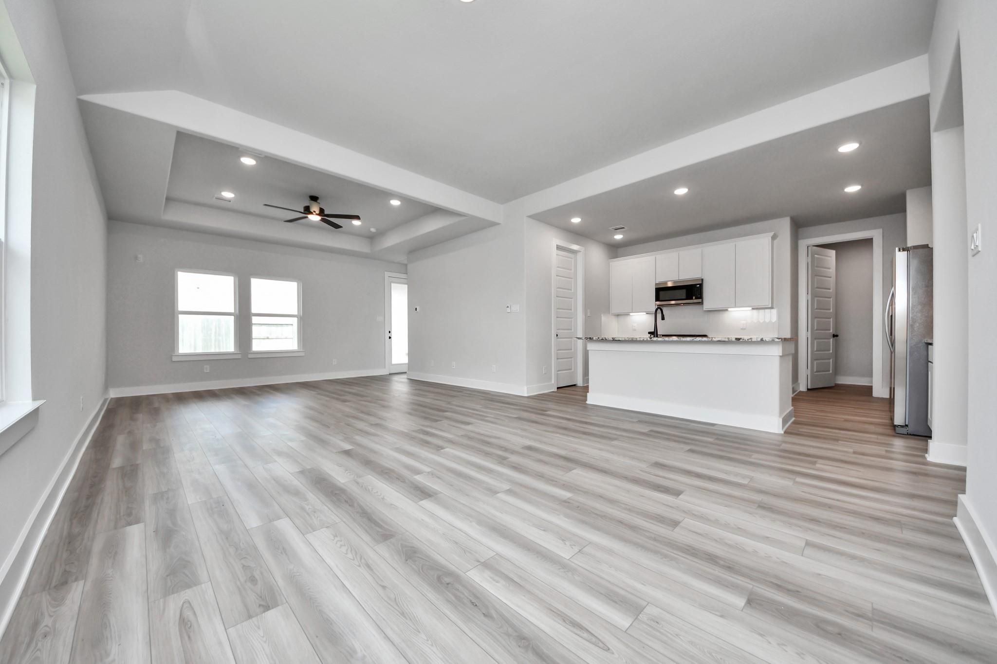 Open-concept living room and kitchen with tray ceiling in The Laguna C floor plan by Davidson Homes in Sunterra, Katy, TX.