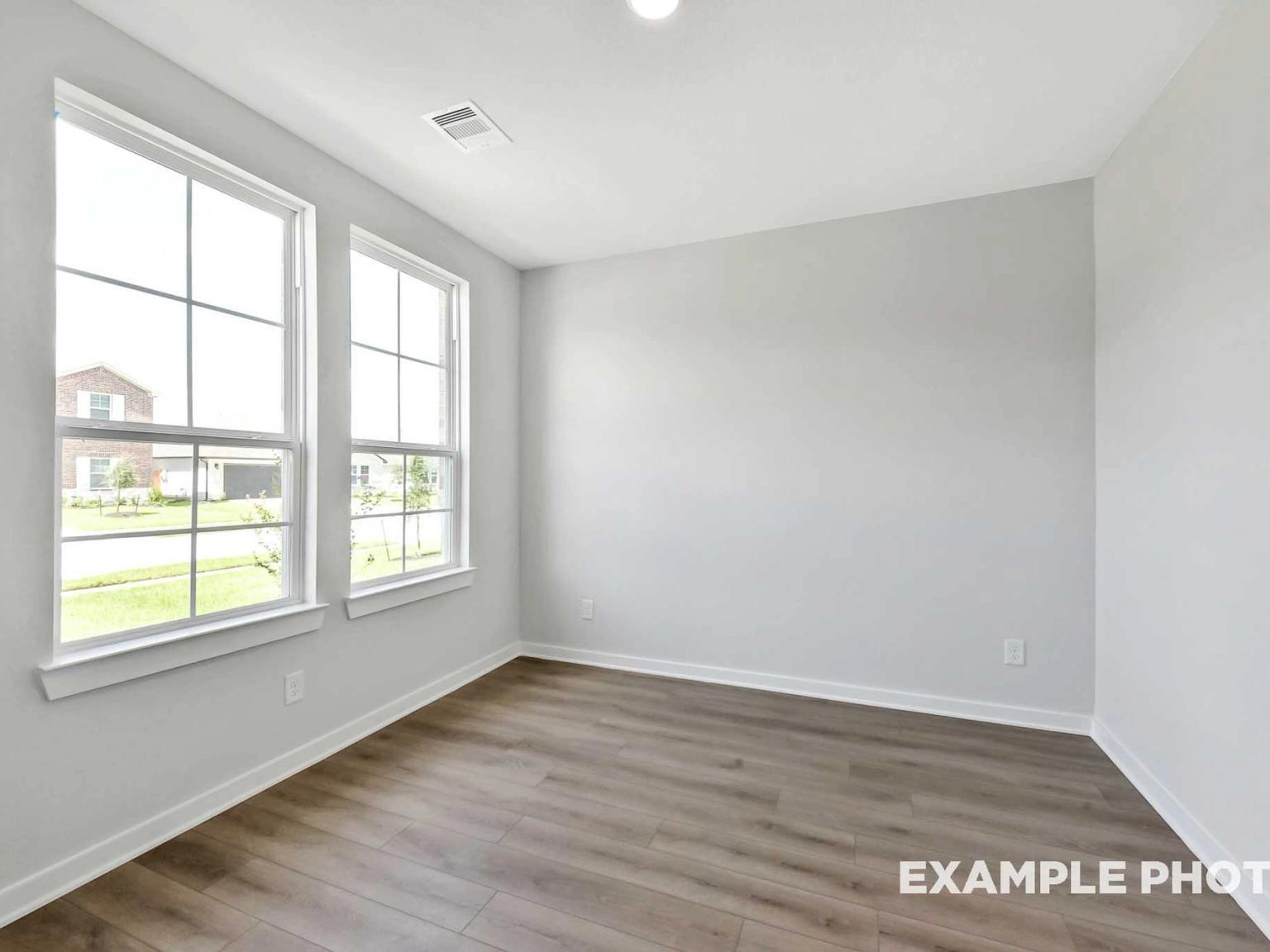 Bright, empty room with light gray walls and wood-look flooring in The Sequoia C floor plan at Sundance Cove, Crosby, TX.