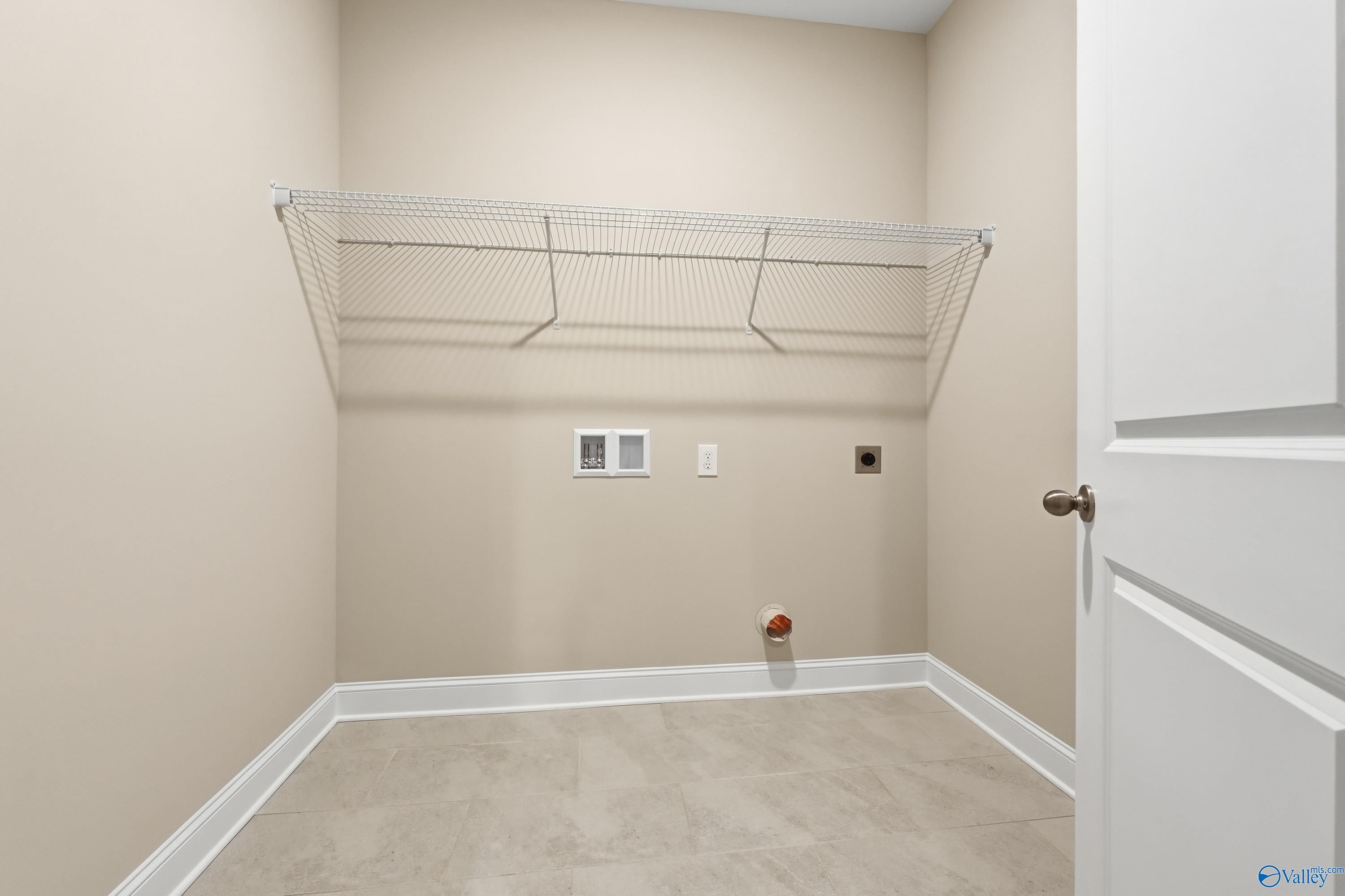 Bright laundry room with wire shelving, washer-dryer hookups, and beige tile floor in The Lanier 4-bedroom home, Meridianville, Alabama