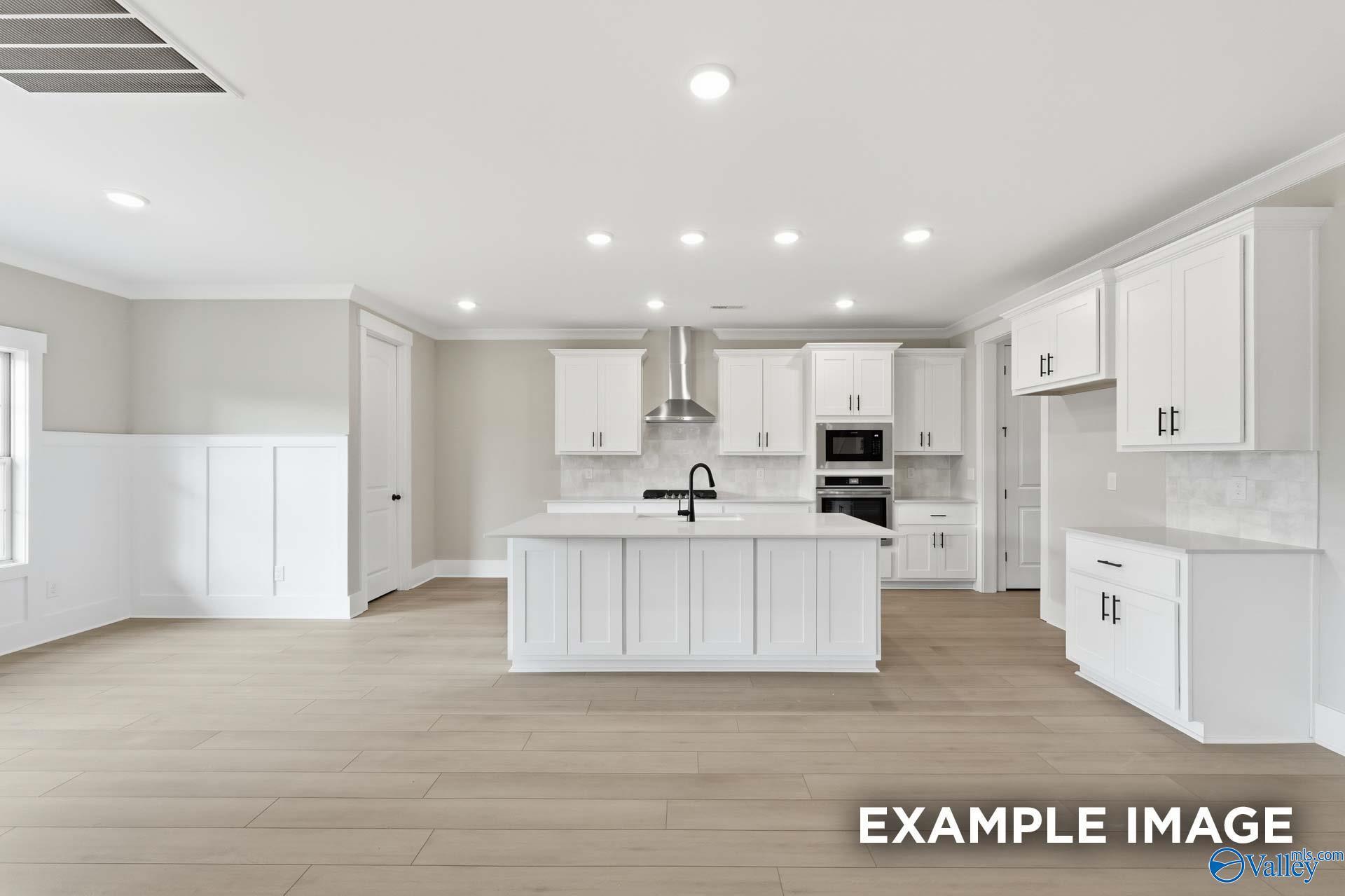 Modern white kitchen with large island, stainless appliances, and open layout in Davidson Homes The Emory, Decatur AL