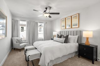 Spacious master bedroom in The Washington H townhome featuring king bed, ceiling fan, neutral decor, and large windows, Davidson Homes Marietta GA
