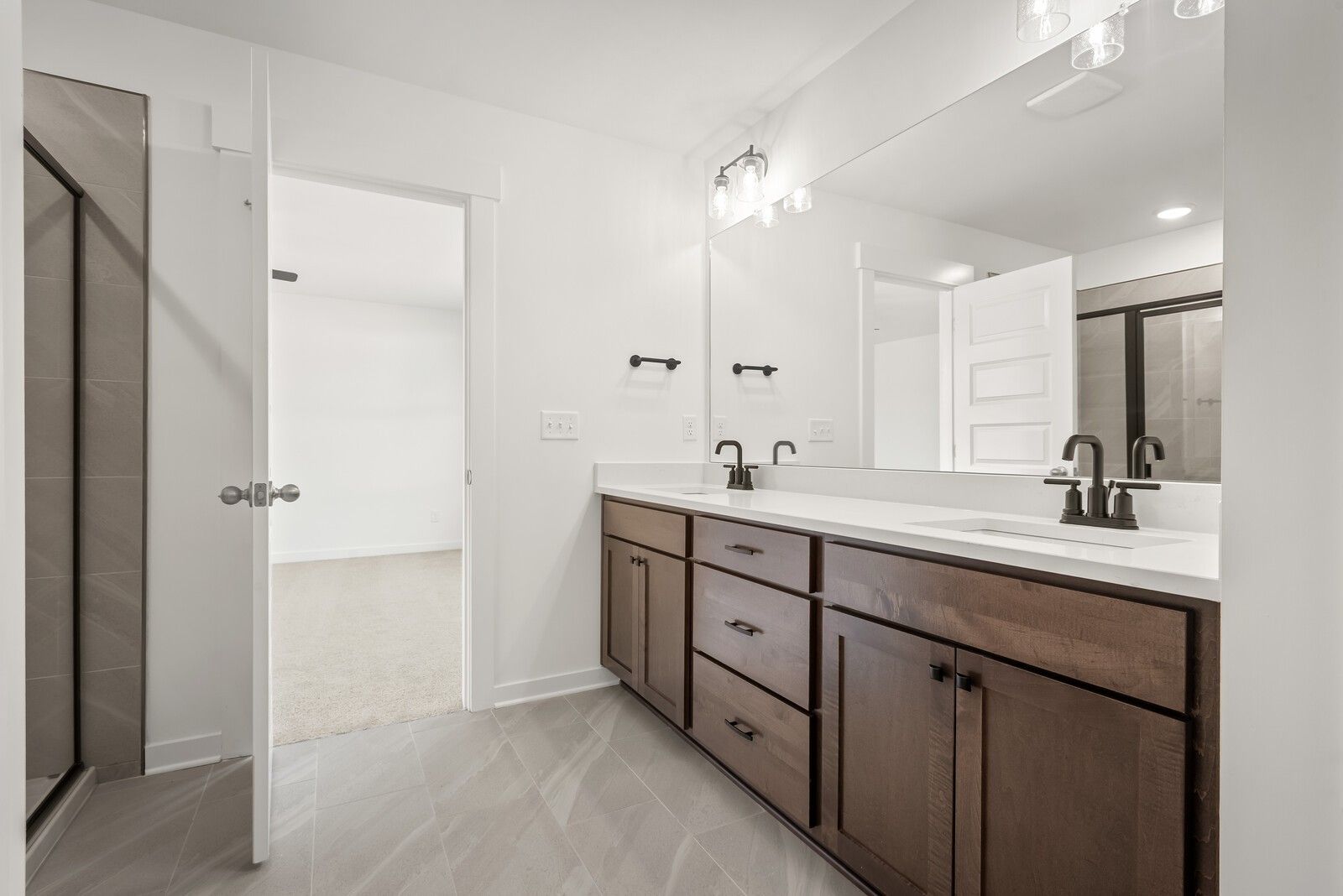 Modern master bathroom with double vanity, shaker cabinets, and glass shower door in Davidson Homes The Logan C, Gallatin, TN