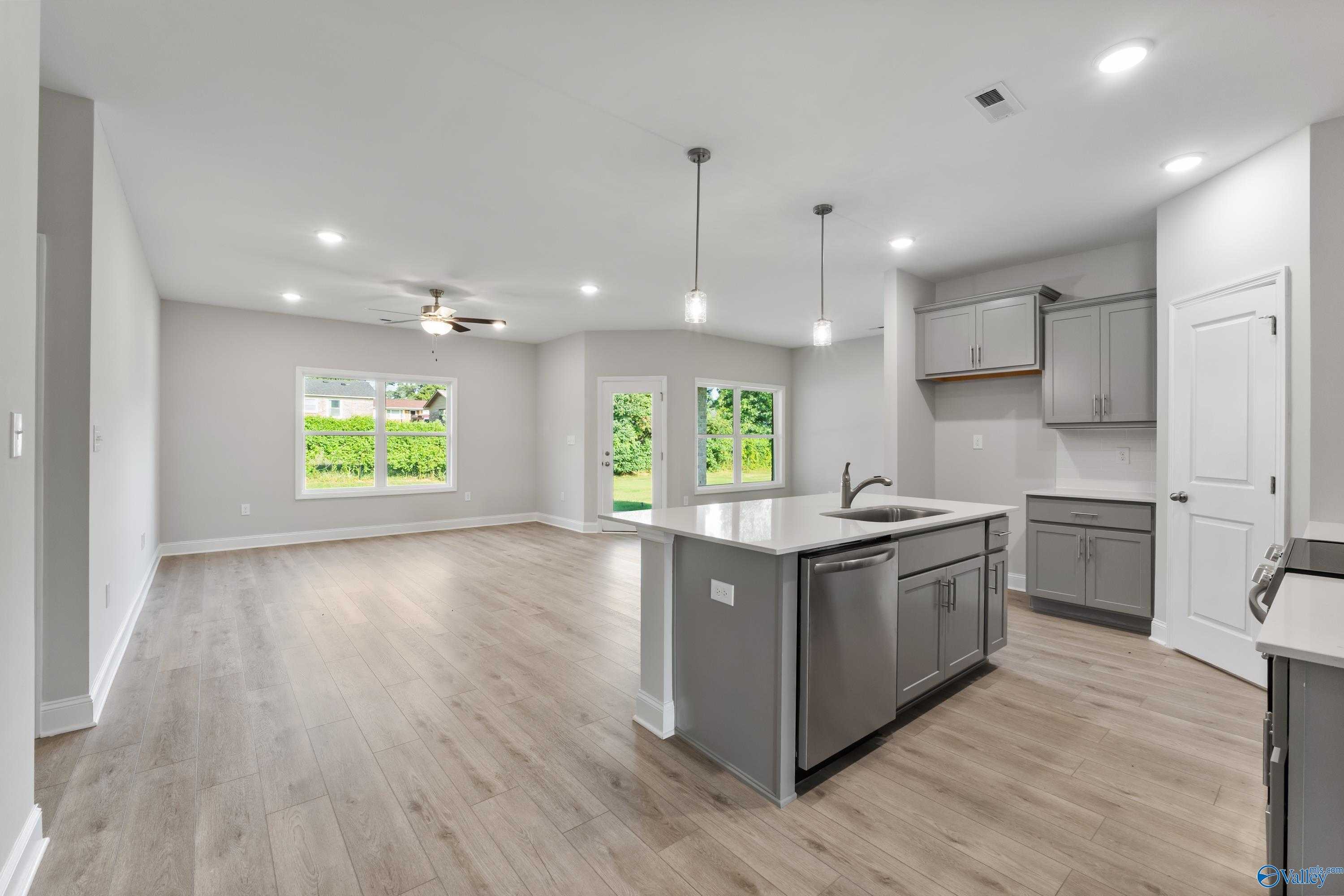 Modern open-concept kitchen with gray cabinets, large island sink, and backyard views in The Daphne C, Davidson Homes, Huntsville AL