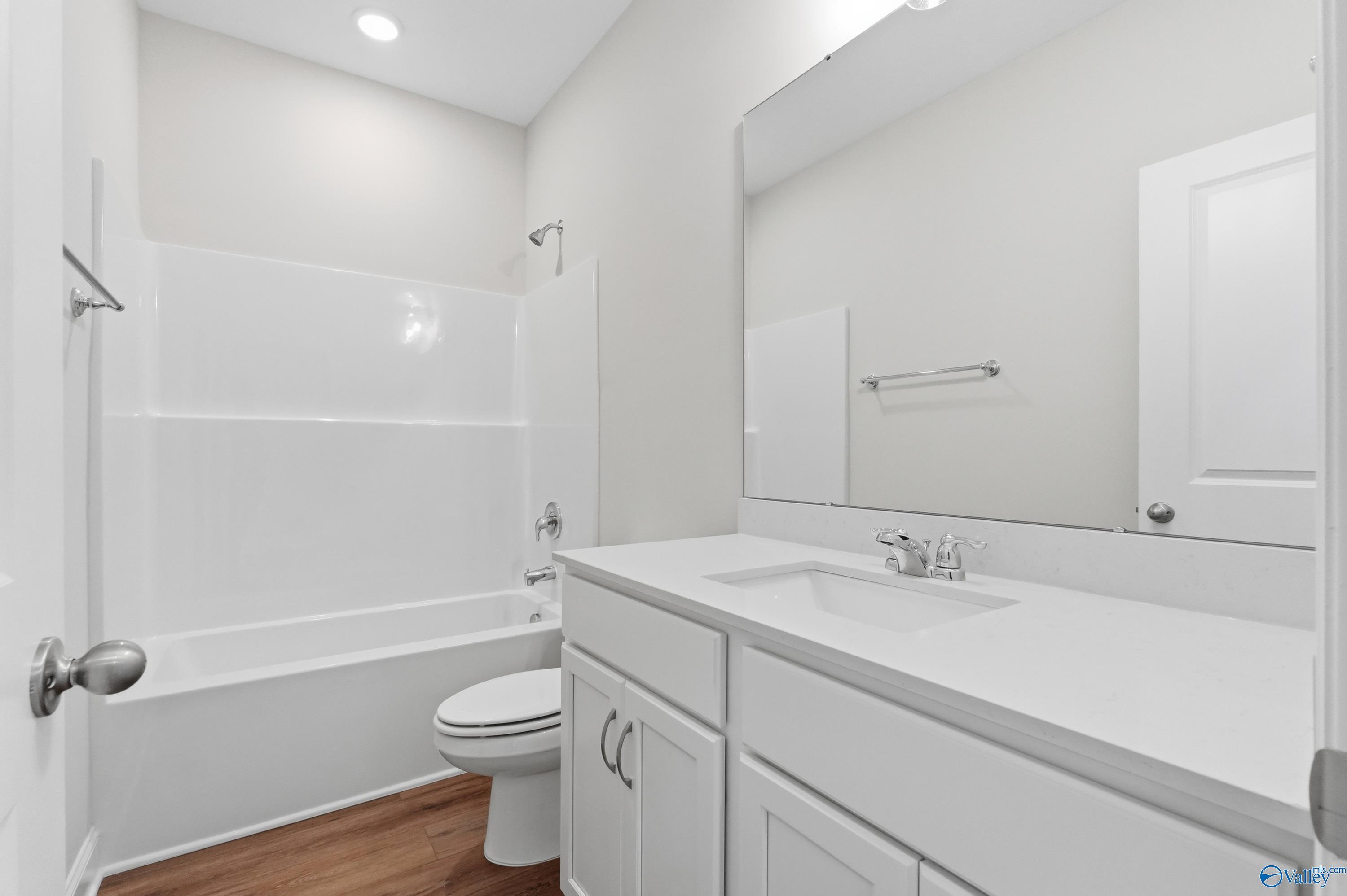Modern full bathroom with white subway tile tub-shower, single vanity sink, and toilet in Davidson Homes The Daphne C, Toney, Alabama