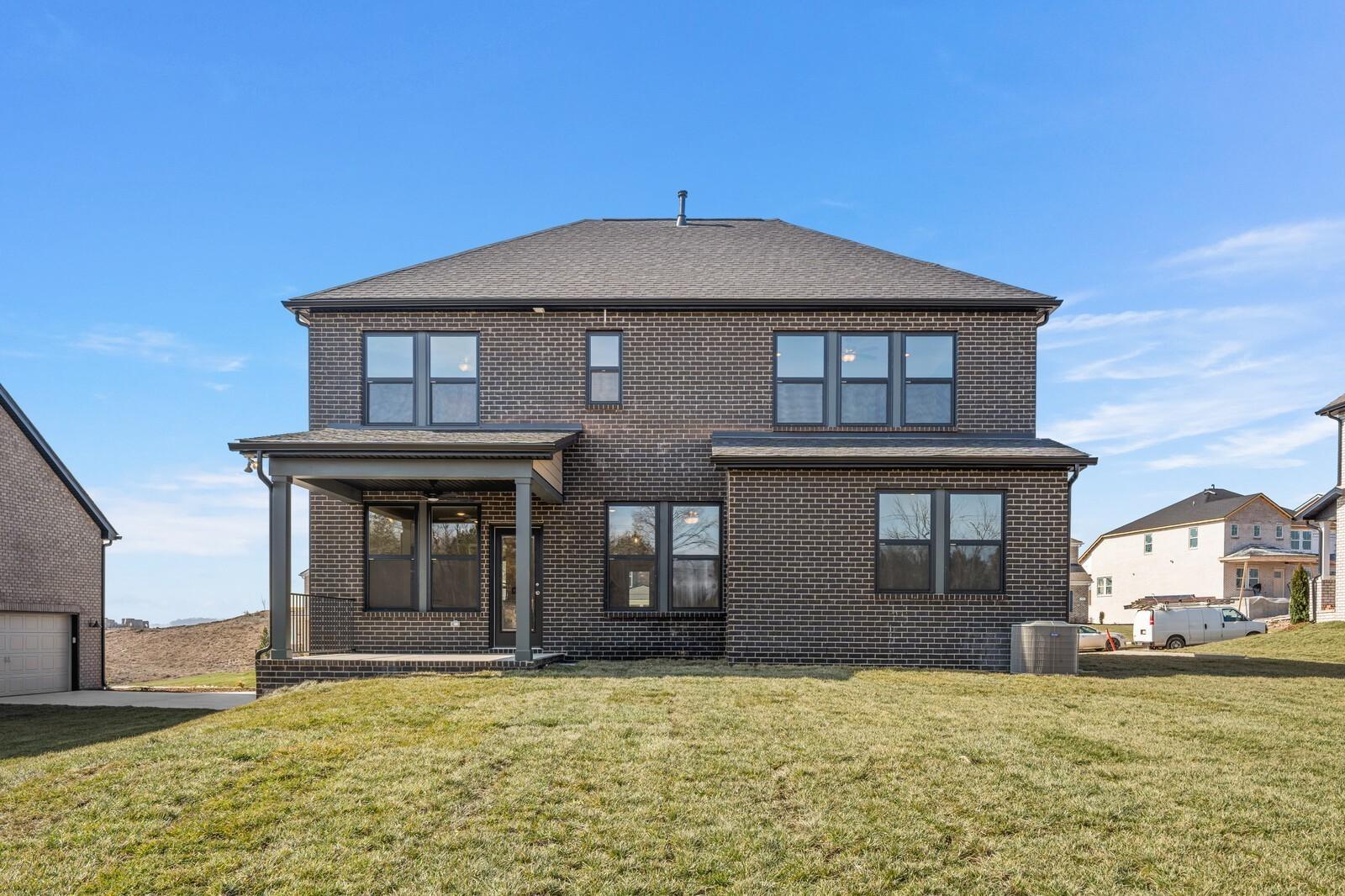 Two-story brick home with covered back porch, large windows, two-car garage, and green yard in Benders Cove, Mt. Juliet, Tennessee - Willow D by Davidson Homes