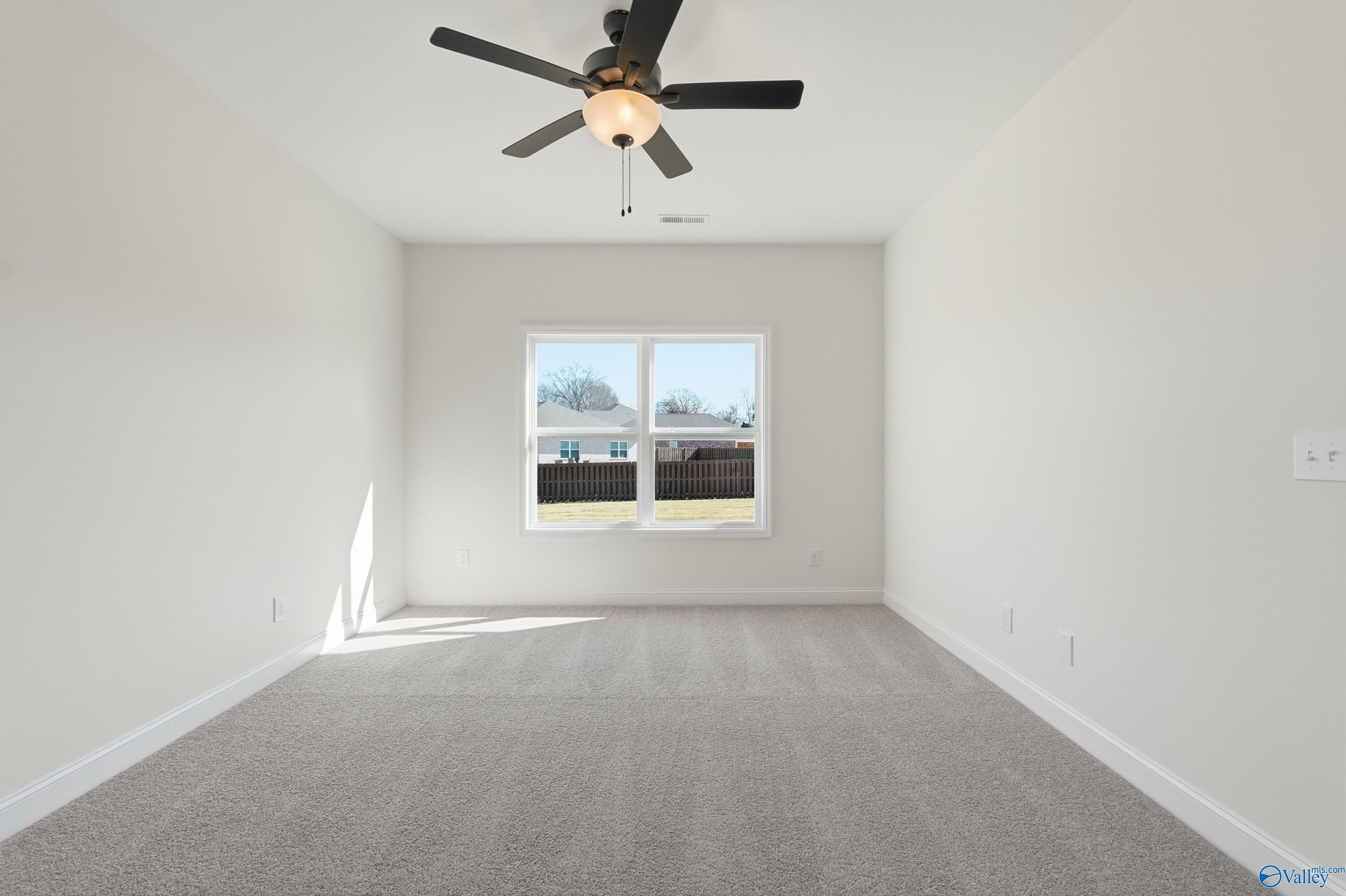 Bright empty bedroom featuring ceiling fan and large window in Davidson Homes The Franklin C, New Market, Alabama