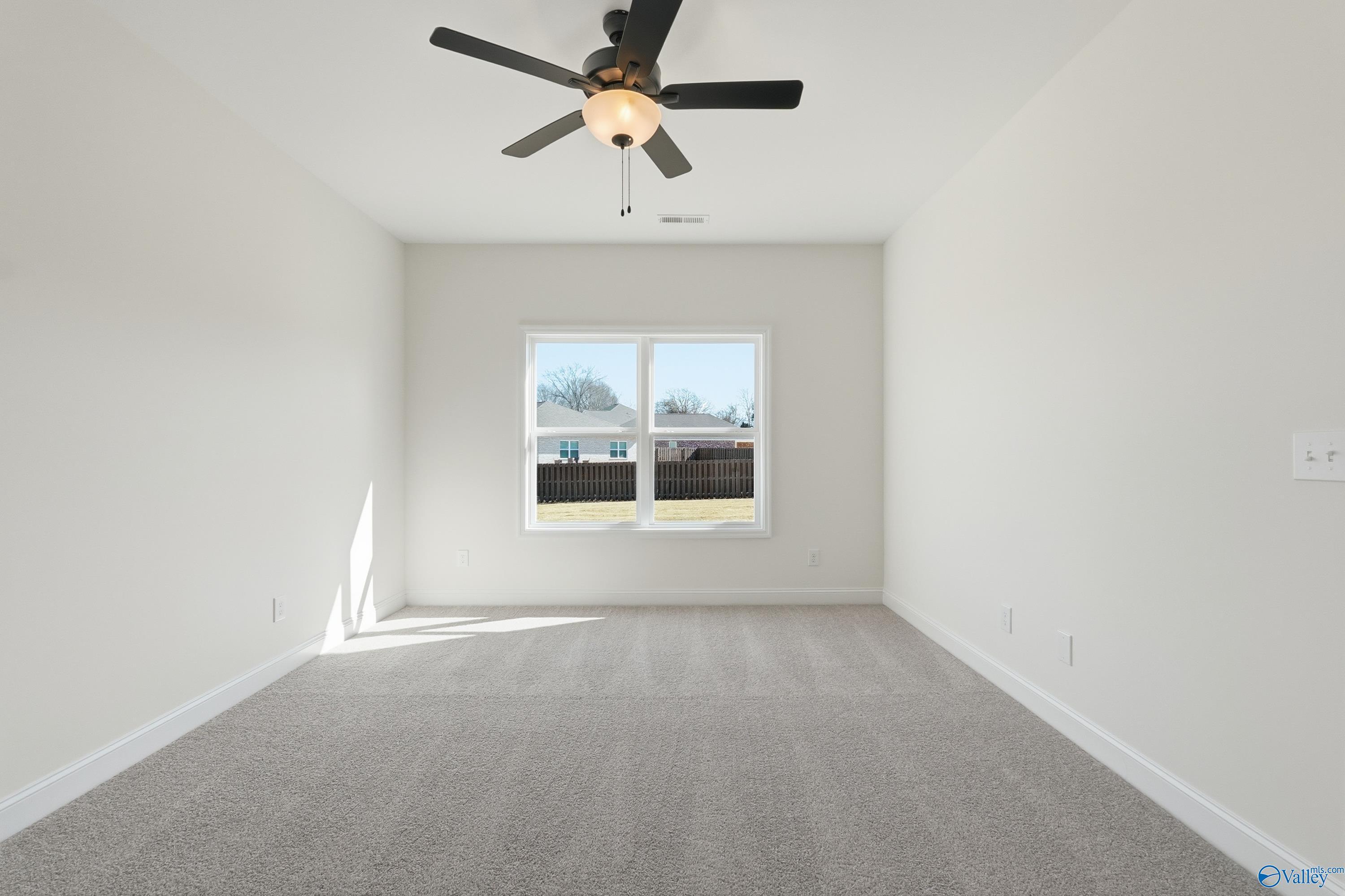 Bright empty bedroom featuring ceiling fan and large window in Davidson Homes The Franklin C, New Market, Alabama
