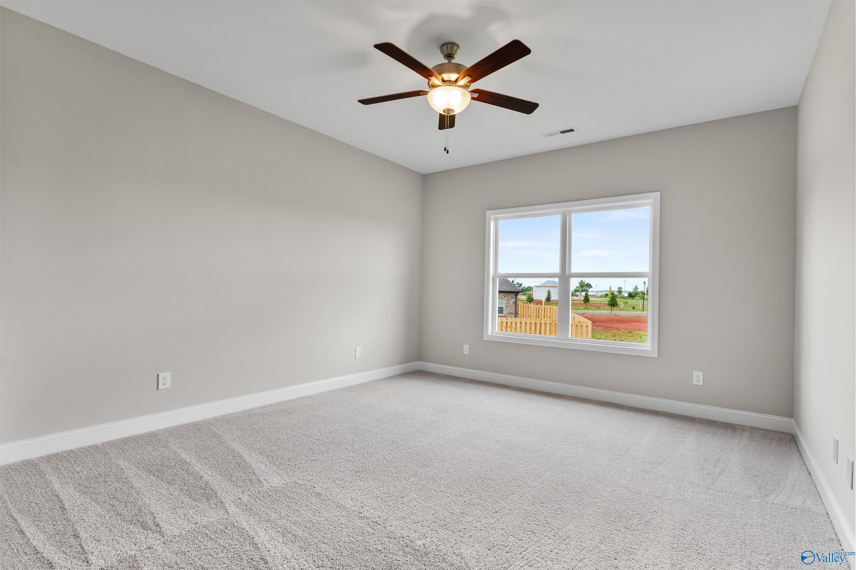 Bright secondary bedroom with ceiling fan, large window overlooking fenced yard in Davidson Homes The Daphne C, Harvest AL