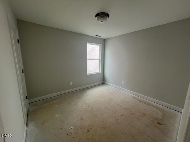 Empty bedroom with light gray walls, window blinds, ceiling fixture, and plywood subfloor in The Adalynn B, Lillington, NC