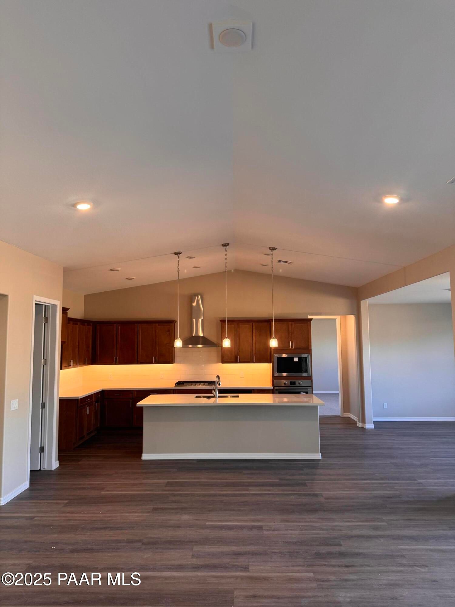 Modern kitchen with dark wood cabinets, white quartz island, stainless appliances, and vaulted ceiling in Davidson Homes Sunrise II A, Prescott AZ