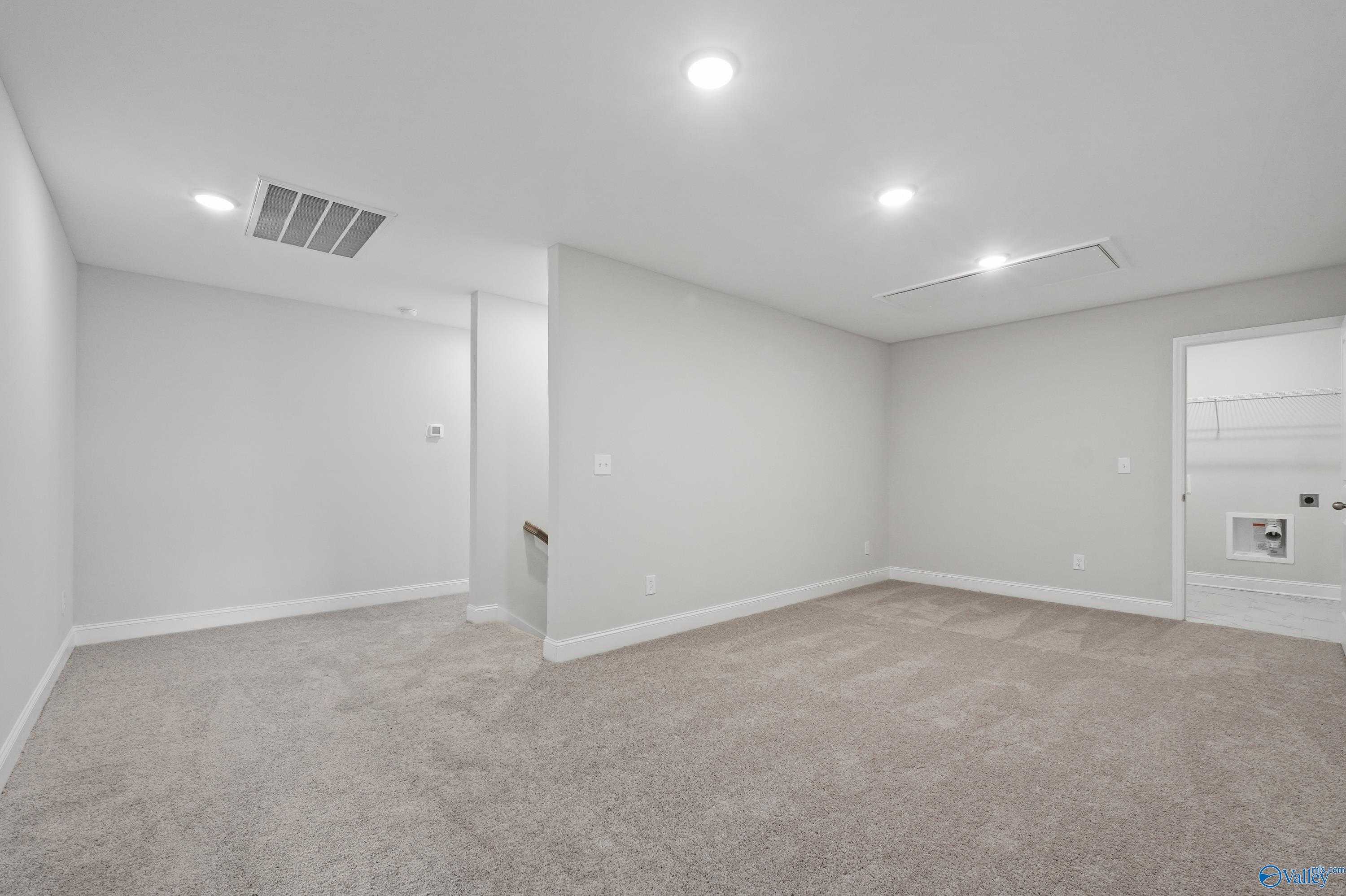 Empty upstairs loft with light gray walls, beige carpet, and recessed lighting in The Camden floor plan by Davidson Homes, Huntsville, AL