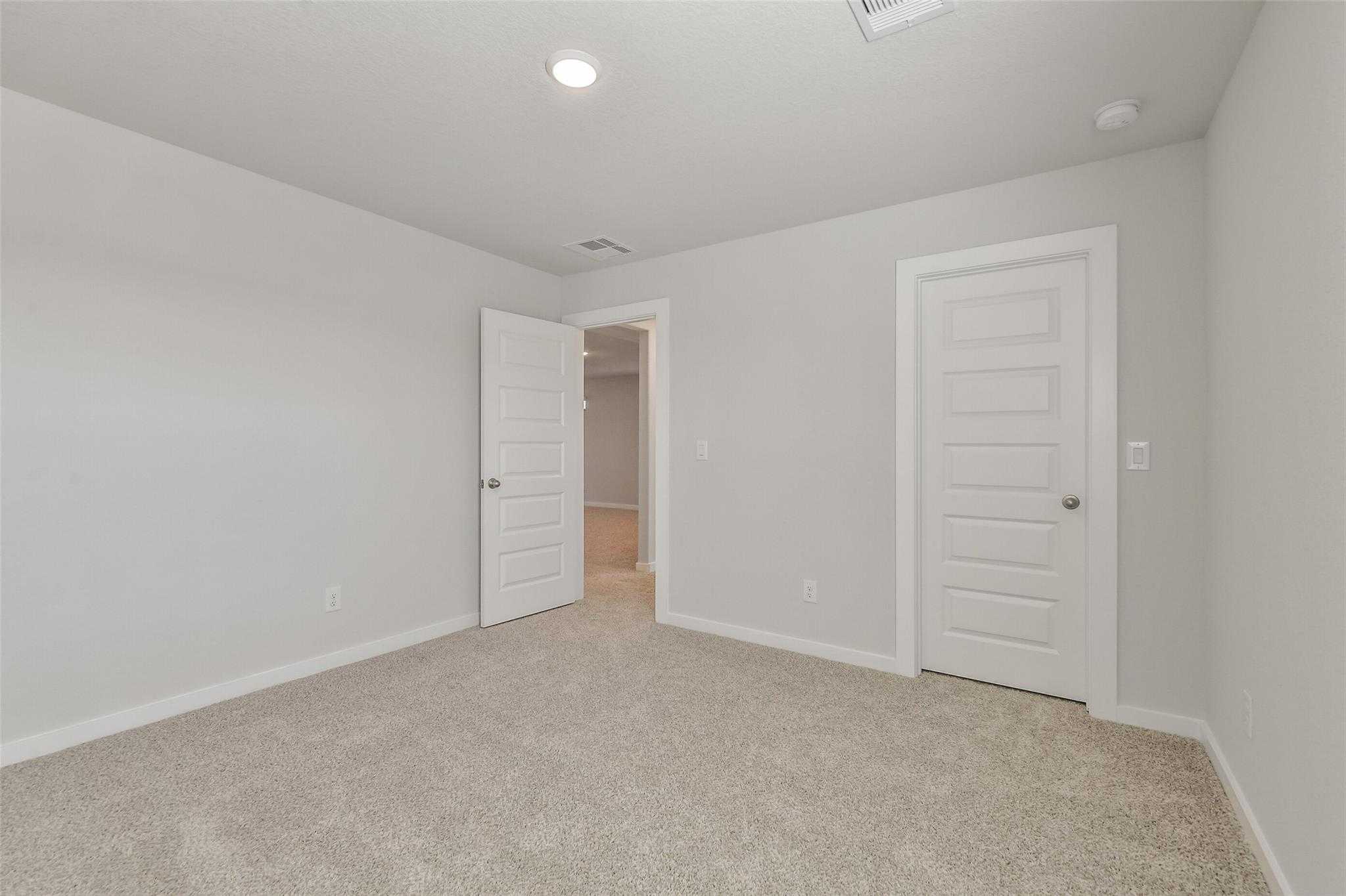 Spacious secondary bedroom with beige carpet, neutral walls, open door to bathroom in Davidson Homes The Rio Grande H, Magnolia, Texas