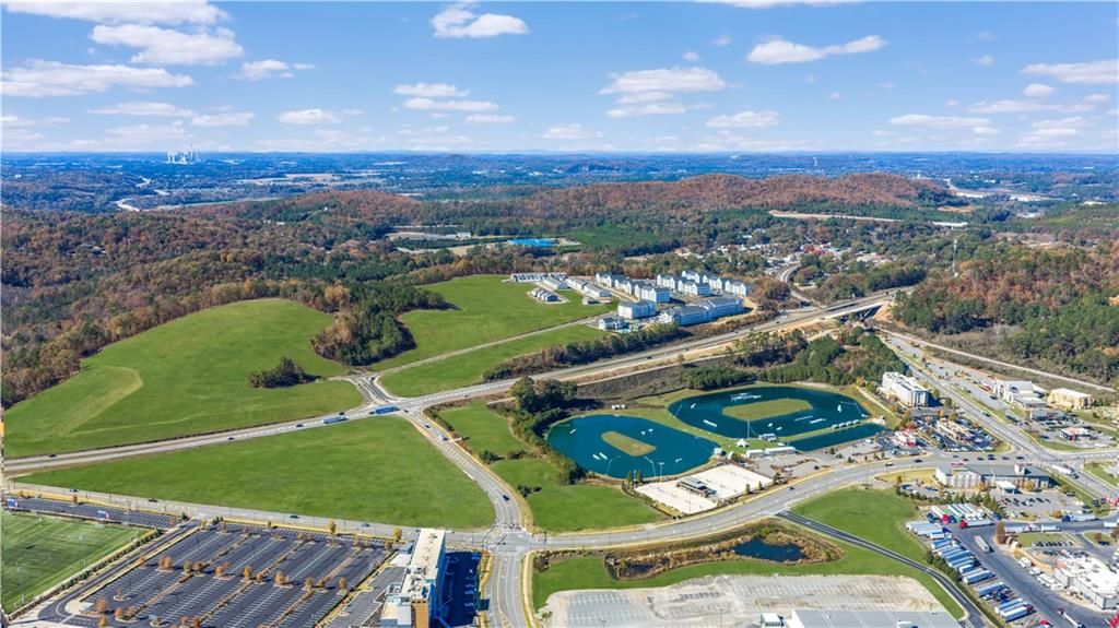 Aerial view of Stegall Village in Emerson, Georgia, featuring green fields, ponds, parking lots, and forested hills around Davidson Homes development