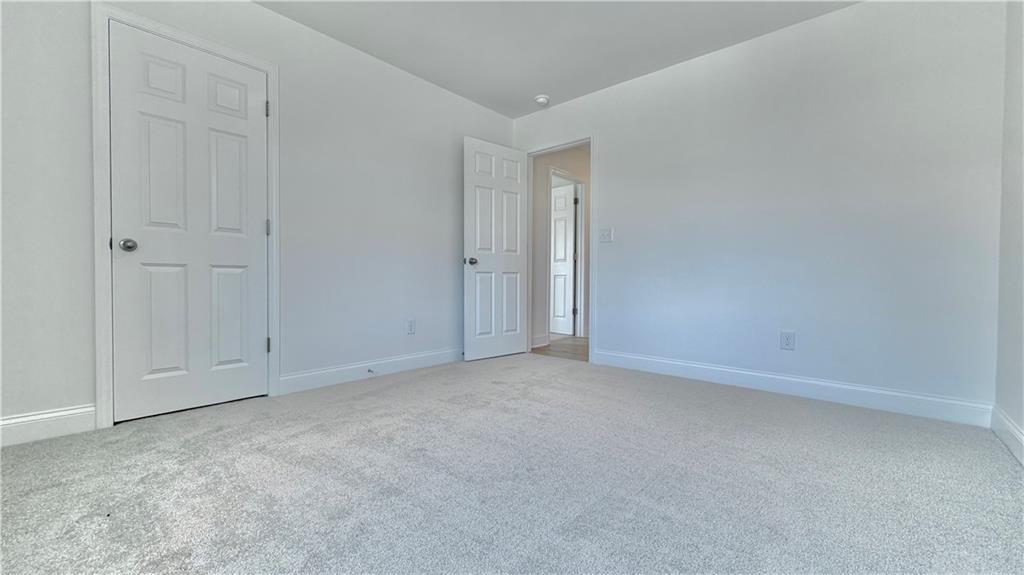 Bright carpeted bedroom with white walls and doors in The Hickory C floor plan at Wehunt Meadows, Hoschton, Georgia.