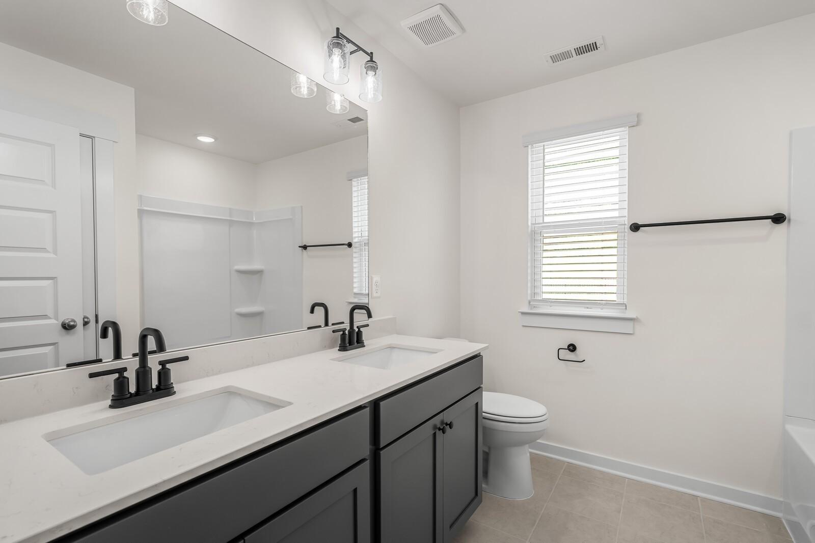 Modern bathroom with double vanity, dark cabinetry, and matte black fixtures in The Willow floor plan, Gallatin, Tennessee.