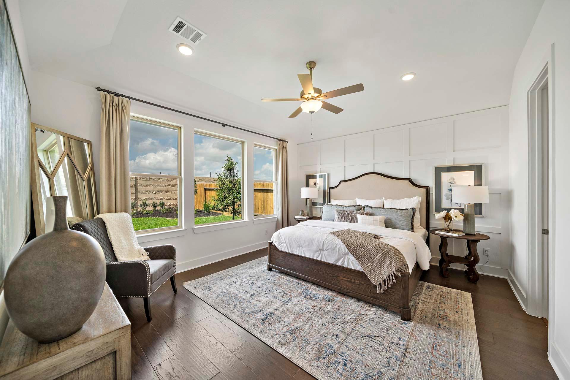 Spacious primary bedroom in Sierra Vista Rosharon TX by Davidson Homes featuring king bed, large windows, and hardwood floors