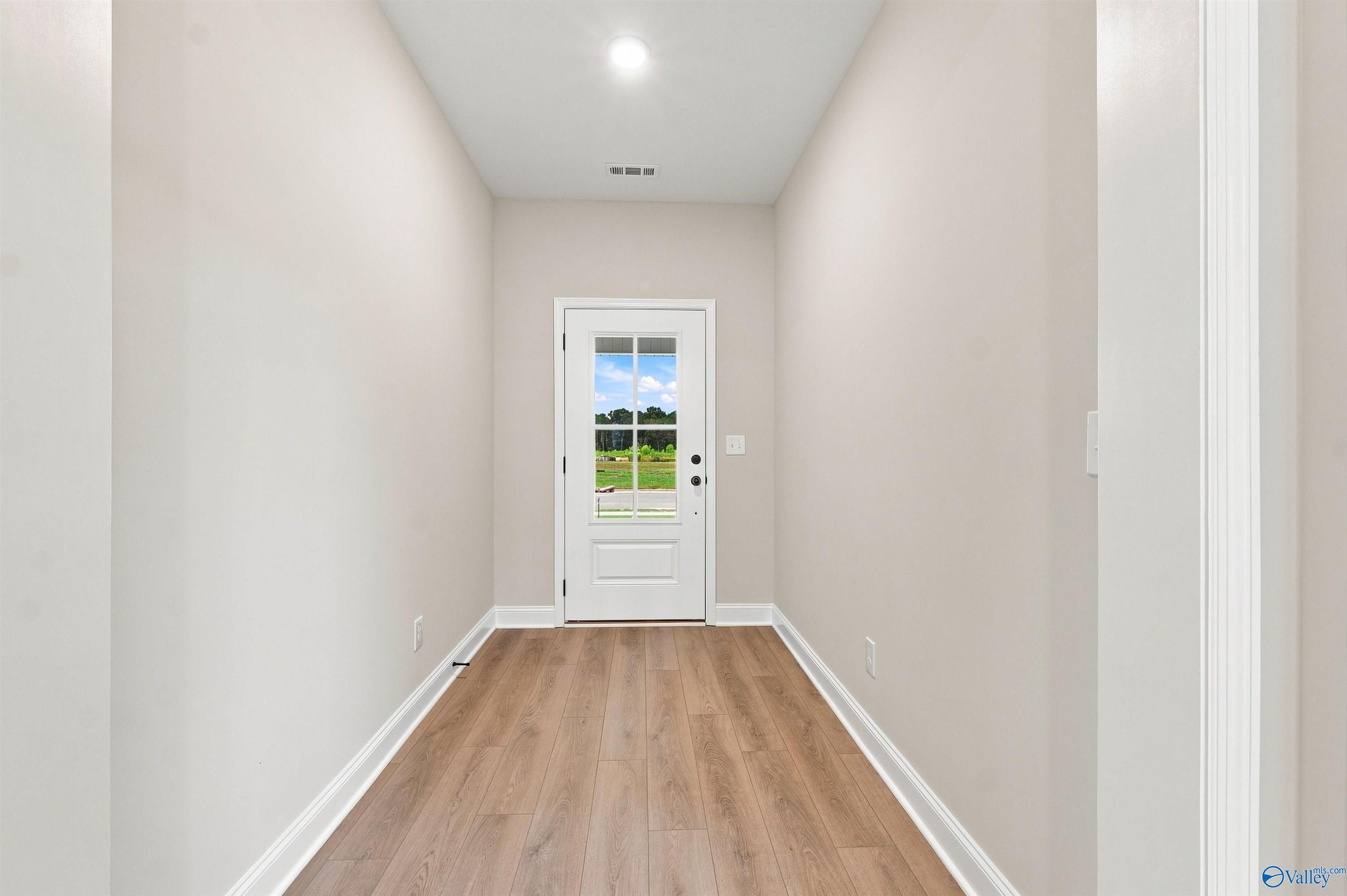 Bright entry foyer with luxury vinyl plank flooring and glass-panel front door in Davidson Homes' The Everett B, Toney, AL