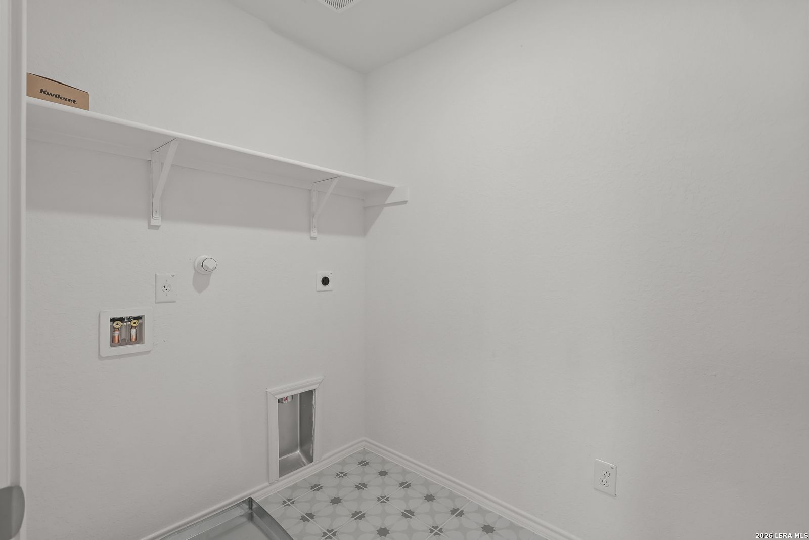 Laundry room with white walls, shelving, and utility hookups in The Gillian C floor plan at Meadows at Oak Creek, TX.