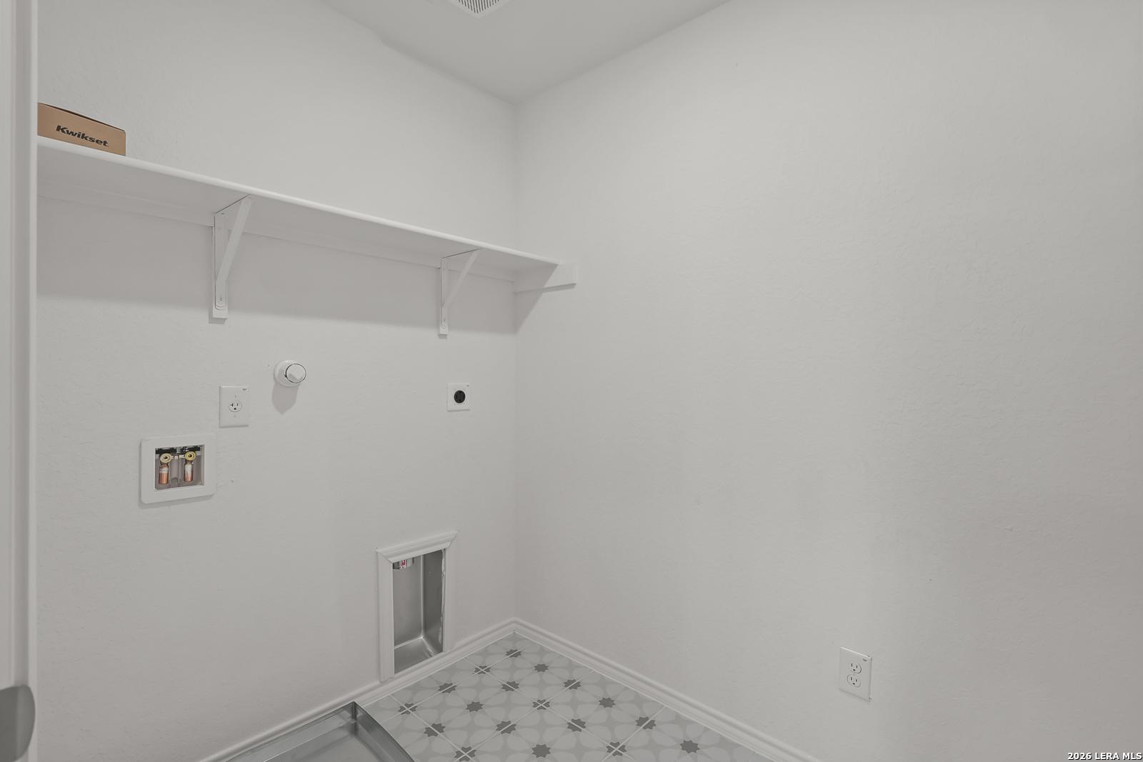 Laundry room with white walls, shelving, and utility hookups in The Gillian C floor plan at Meadows at Oak Creek, TX.