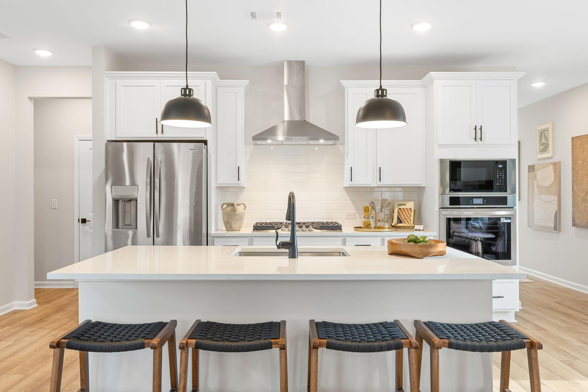 Modern white kitchen with island, stainless appliances, pendant lights at Links Crossing in Auburn, Alabama