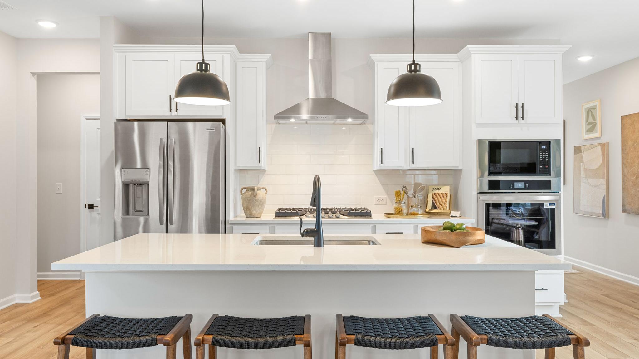 Spacious modern kitchen in Greene Farms Cartersville GA by Davidson Homes with white shaker cabinets, stainless steel appliances, and island