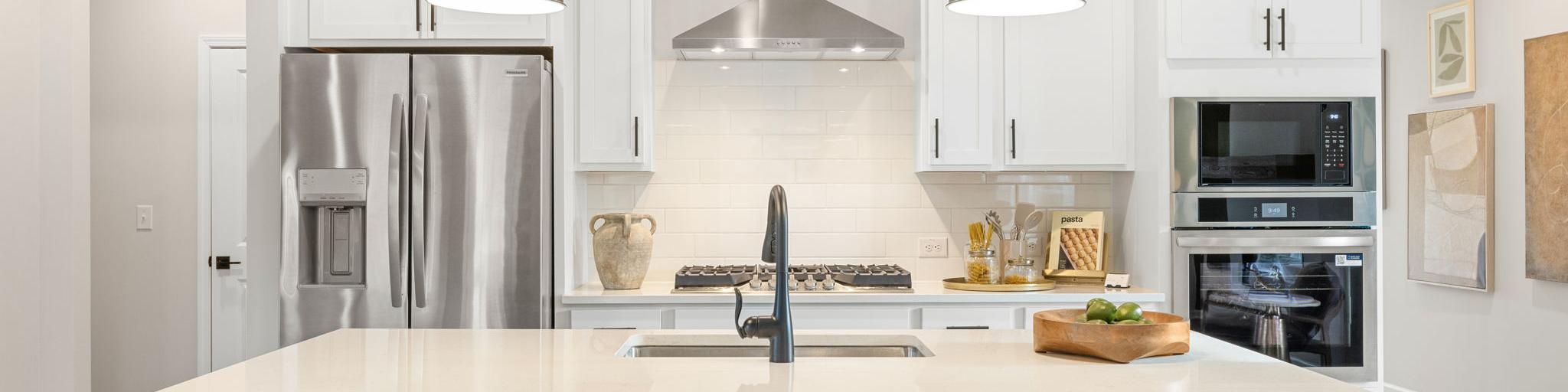 Spacious modern kitchen in Greene Farms Cartersville GA by Davidson Homes with white shaker cabinets, stainless steel appliances, and island