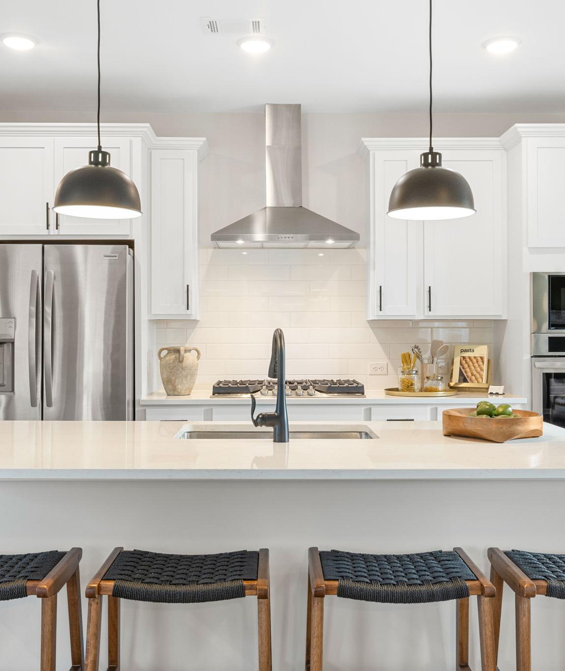 Spacious modern kitchen in Cedar Farms Winder GA with white shaker cabinets, dark quartz island, gas cooktop, and hardwood floors