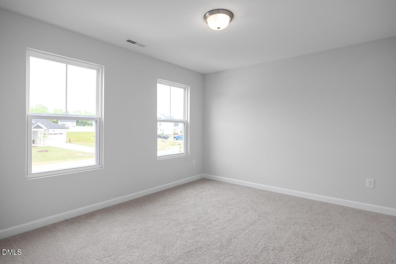 Spacious empty bedroom with gray walls, large double windows, neutral carpet in 5-bed Davidson Homes The Hickory II B, Zebulon, NC