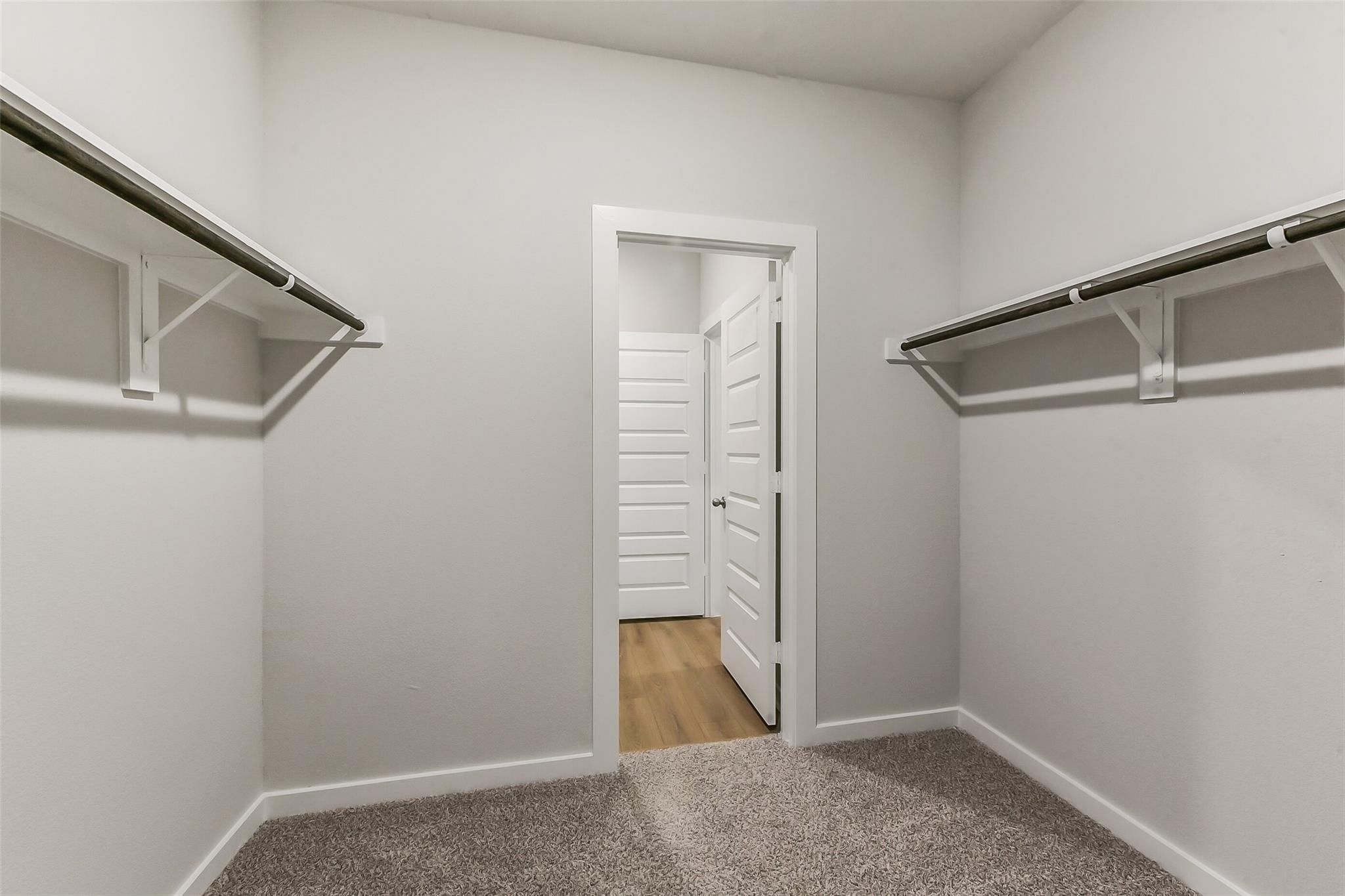 Spacious walk-in closet with white shelving and adjacent bathroom in Davidson Homes The Brazos E, Magnolia, Texas