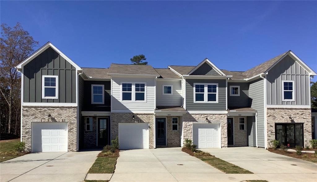 Modern two-story townhomes with gray board-and-batten siding, white trim, and one-car garages in Stegall Village, Emerson, Georgia