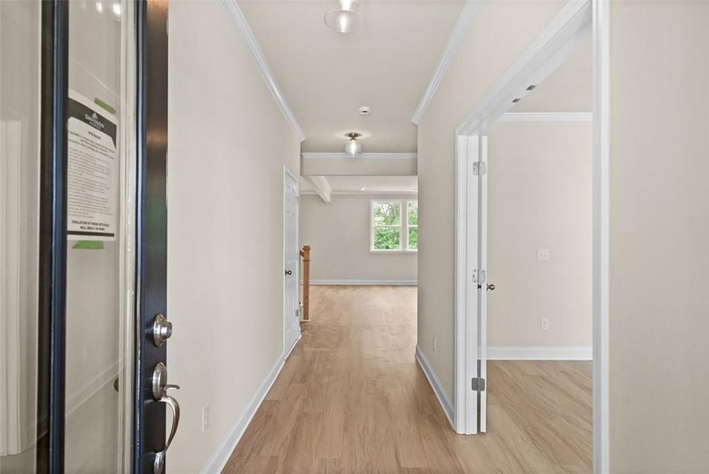 Bright entry hallway with hardwood floors, beige walls, and front door in Davidson Homes The Hickory B at Wehunt Meadows, Hoschton