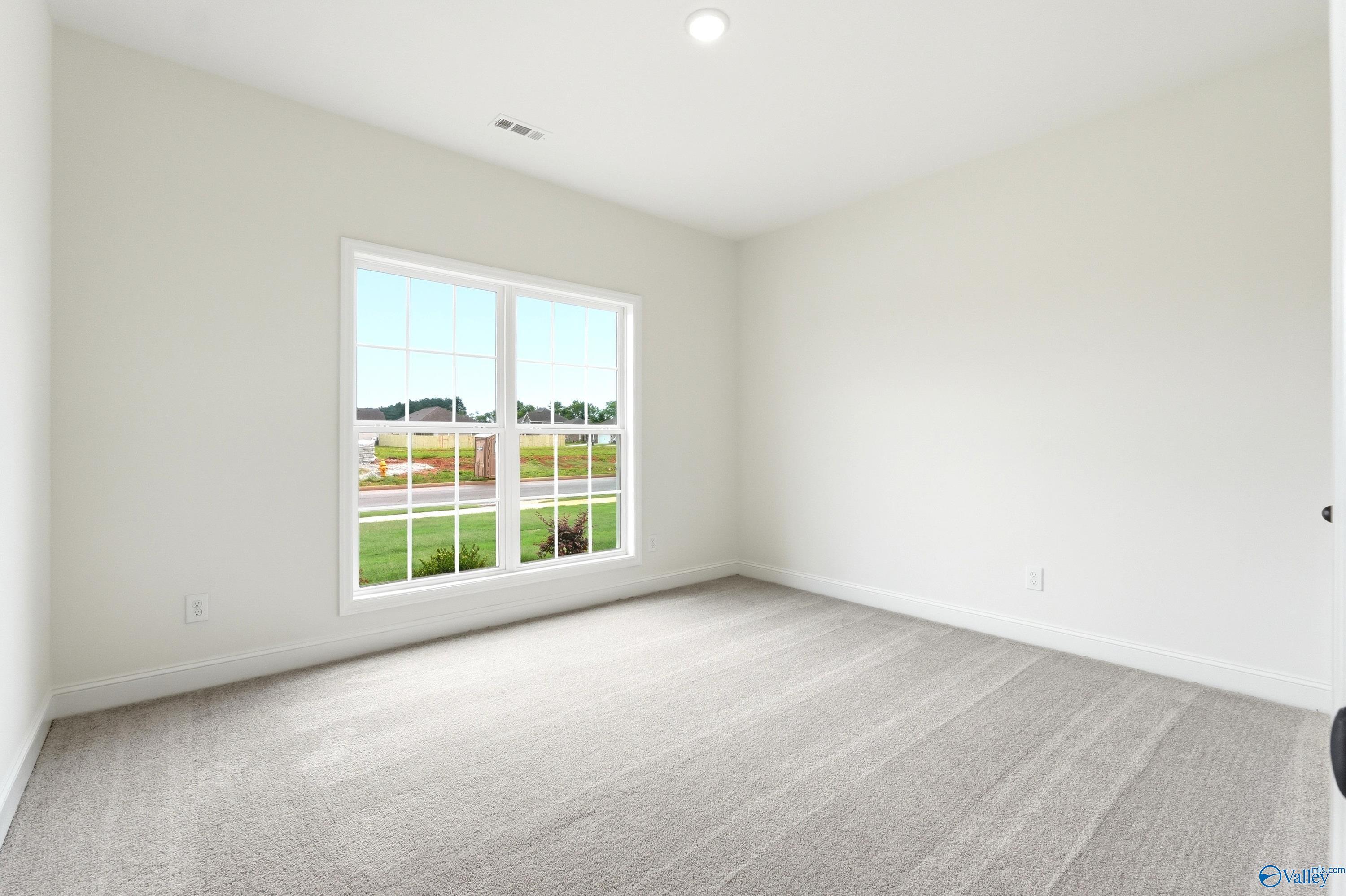 Bright bedroom with neutral carpet and large window in a Davidson Homes Daphne C floor plan in Ivy Hills, Toney, AL.