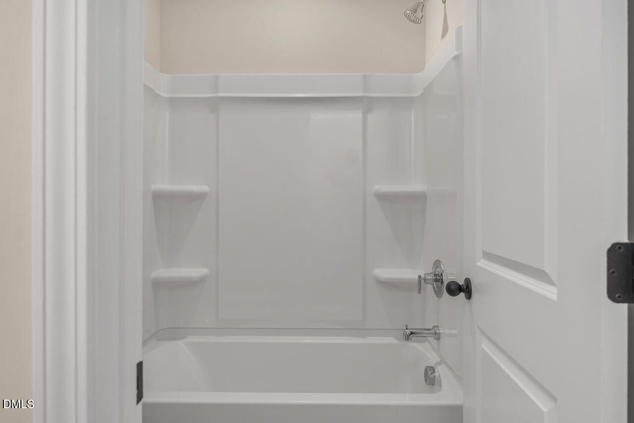 White bathtub shower combo with built-in shelves in Davidson Homes The Mitchell Interior bathroom, Knightdale, North Carolina