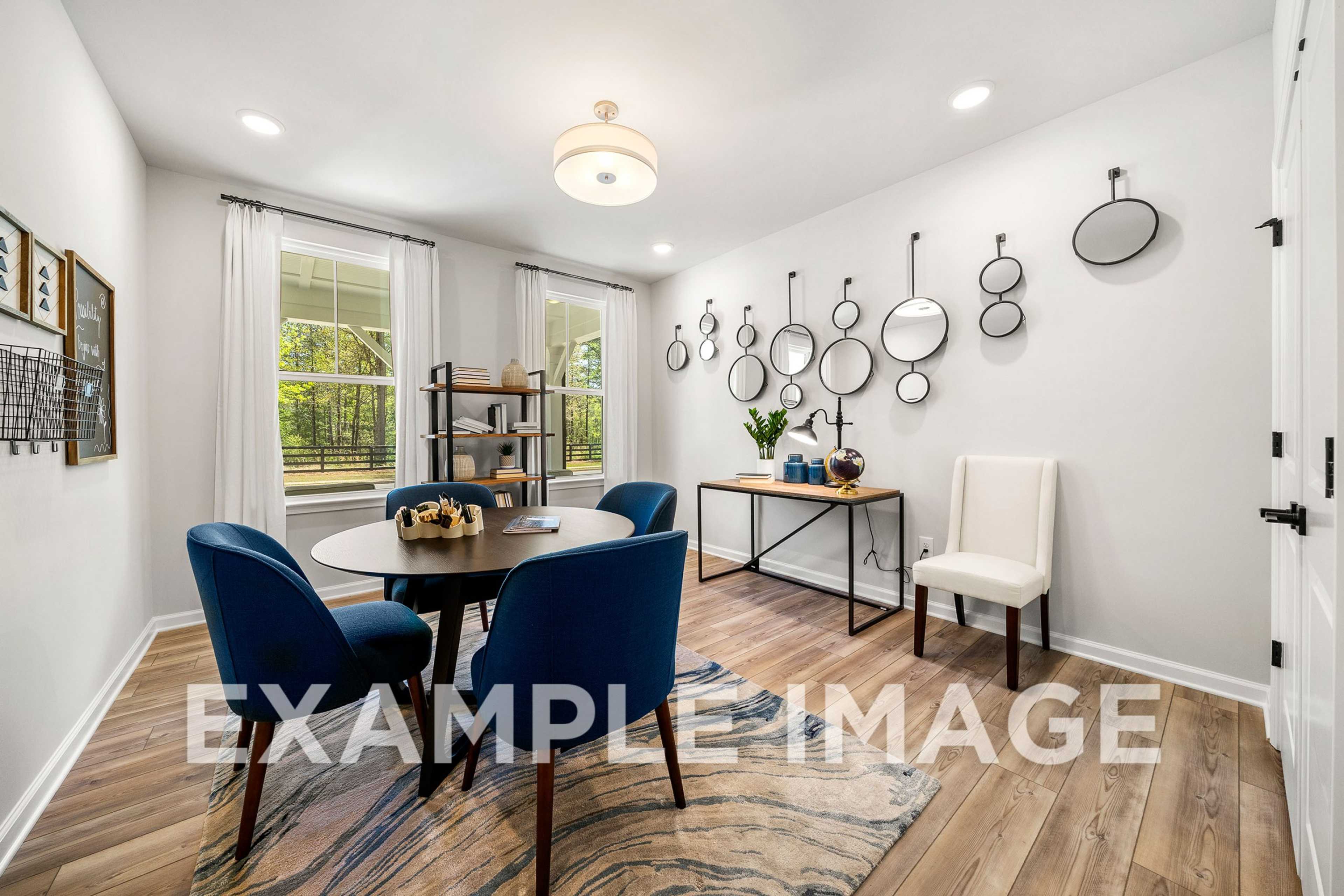 Spacious dining room in The Hickory with round table, navy blue chairs, chandelier, wall mirrors, and console decor
