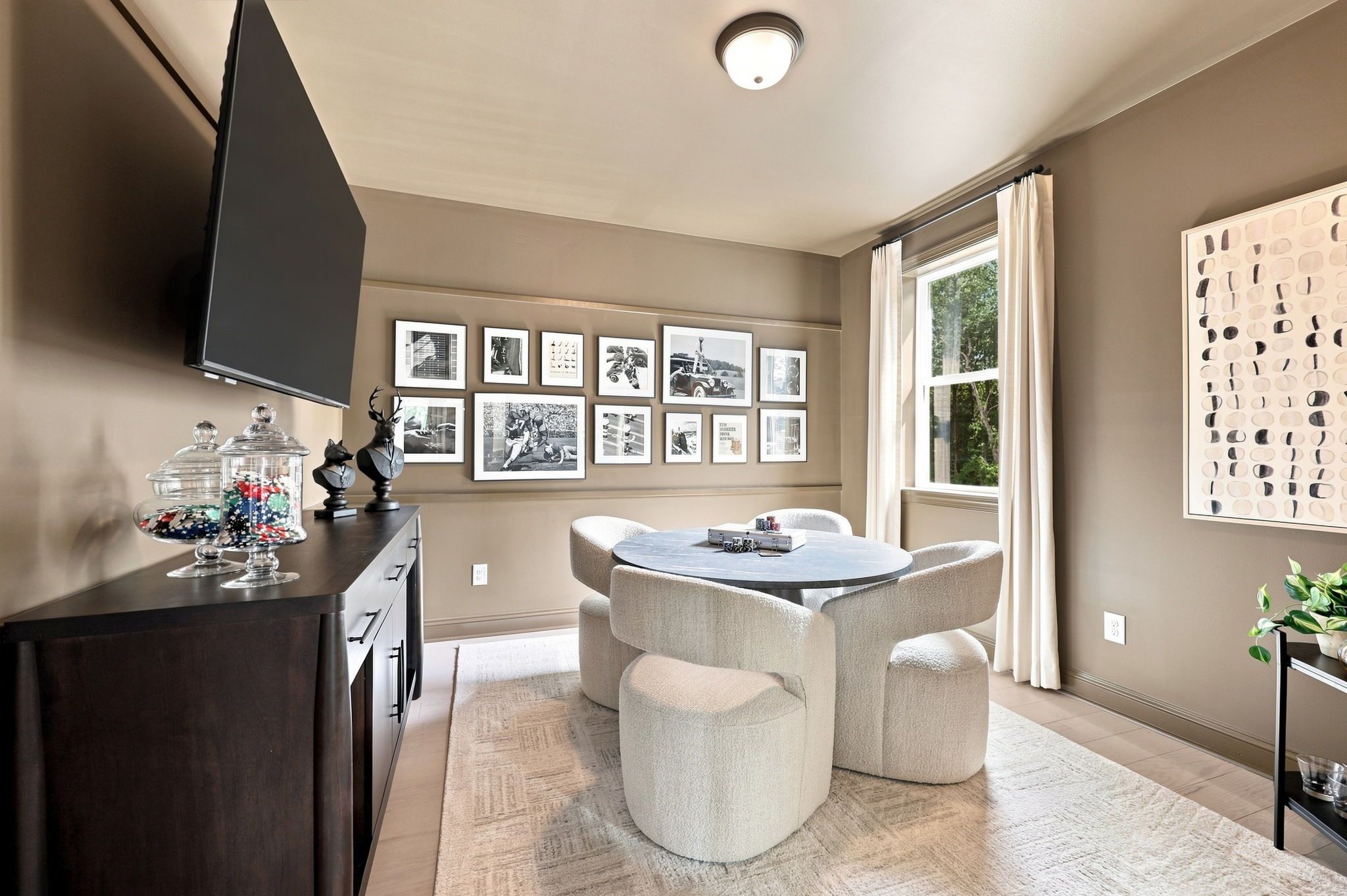 Modern game room in The Barrington C home design featuring a round table, plush seating, and gallery wall decor.
