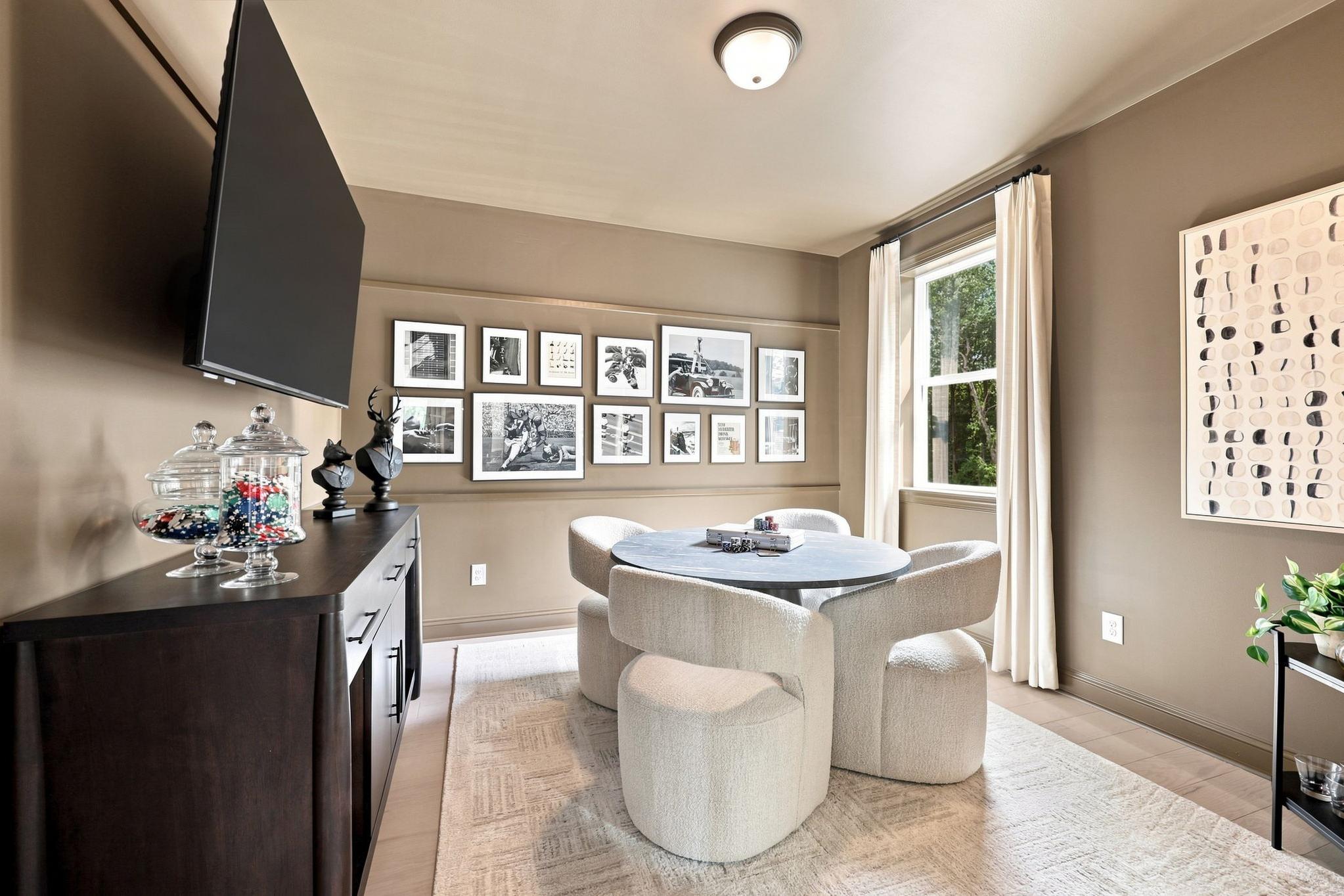 Modern game room in The Barrington C home design featuring a round table, plush seating, and gallery wall decor.
