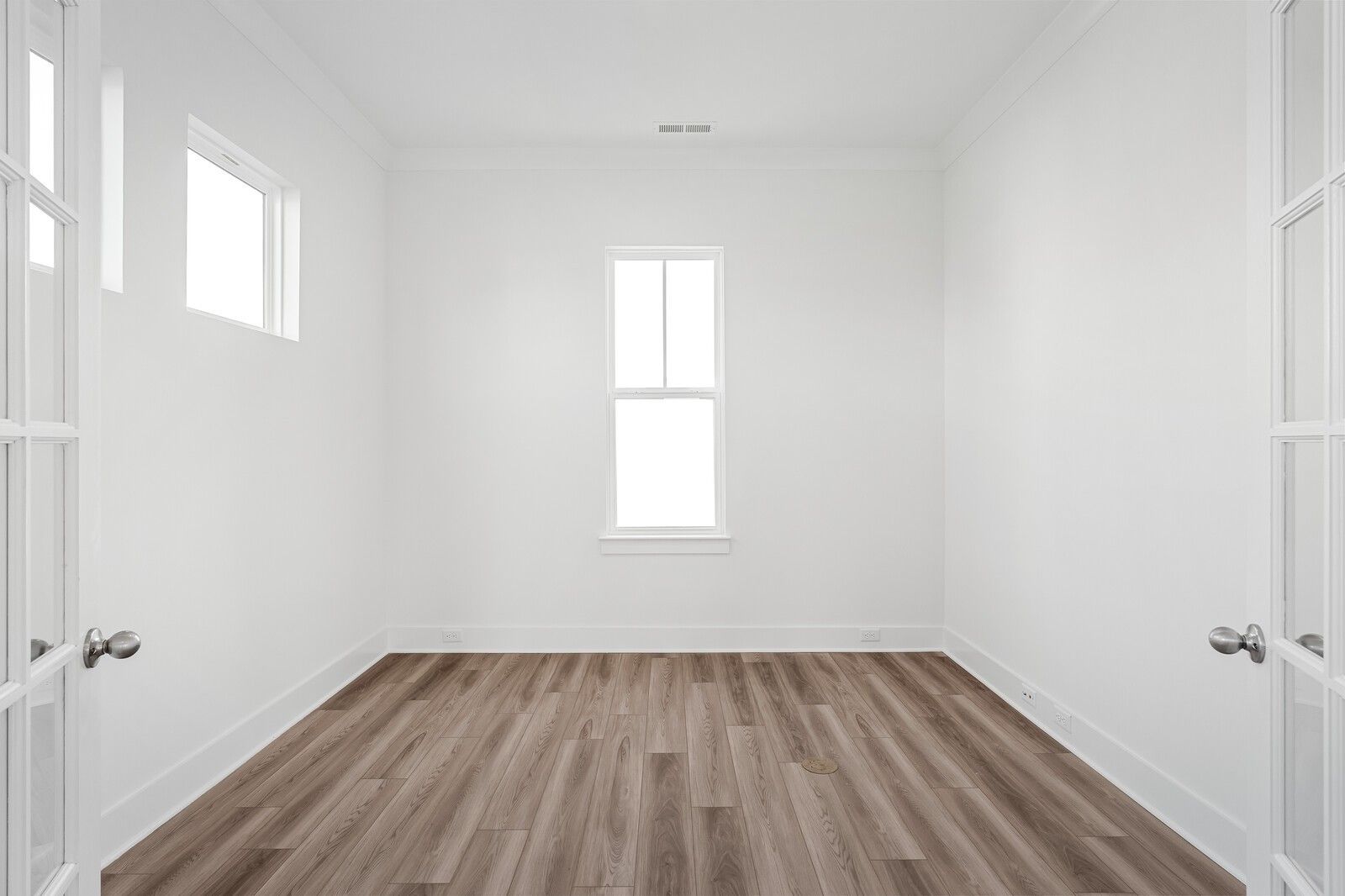 Empty bedroom with white walls, hardwood floors, French doors, and large windows in The Alston A by Davidson Homes, Murfreesboro, TN