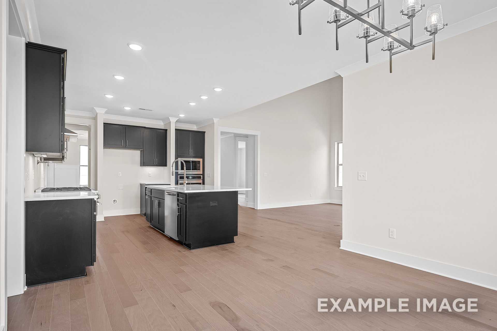 Spacious kitchen in The Hawkins home with dark cabinets, large central island, stainless appliances, and open layout