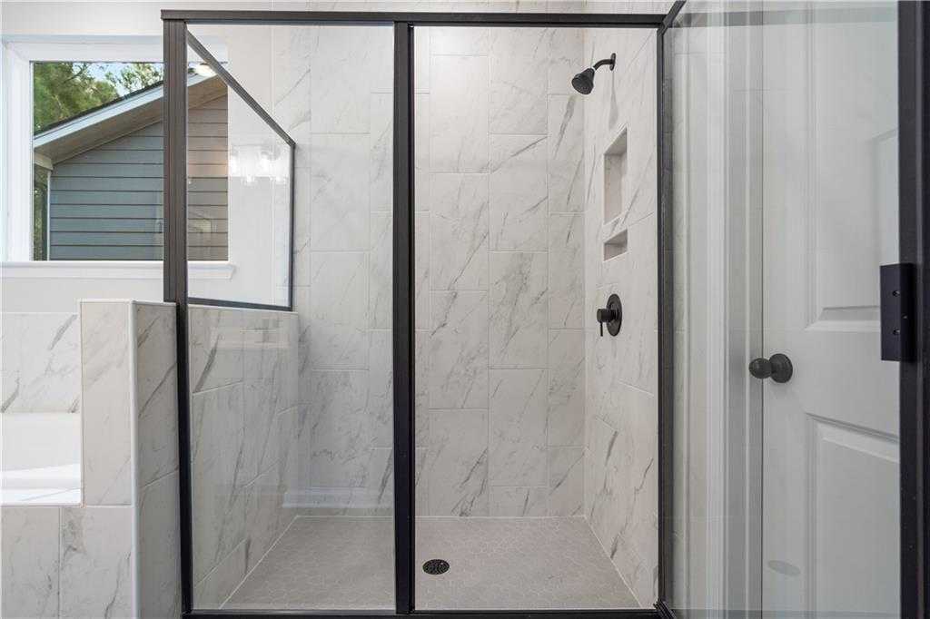 Frameless glass walk-in shower with white subway tile, rainfall showerhead, and freestanding tub in master bathroom of Davidson Homes The Daphne B, Loganville, GA