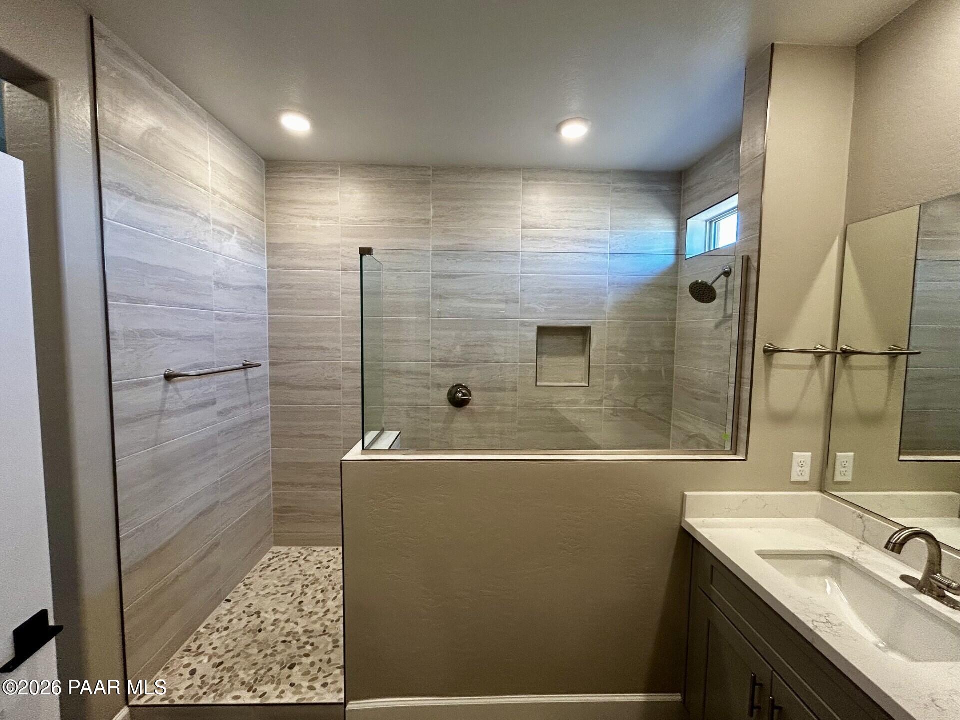 Walk-in tiled shower with glass enclosure and pebble floor in Davidson Homes Harmony C plan at Pronghorn Ranch, Prescott.