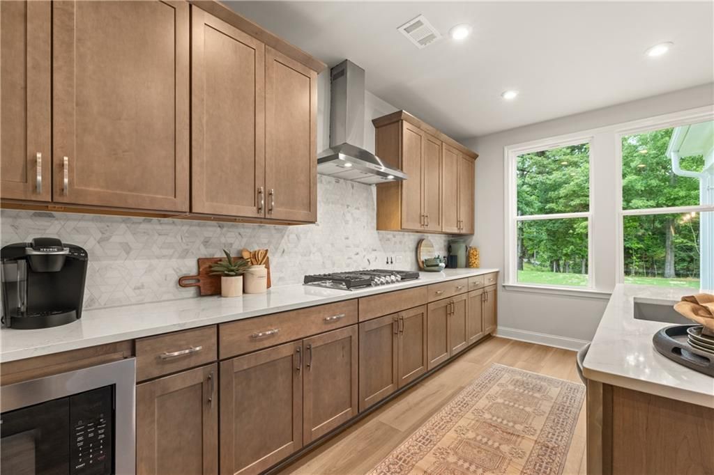 Modern kitchen with wood cabinets, gas cooktop, marble backsplash, and white countertops in Davidson Homes Danbury E plan, Buford, GA