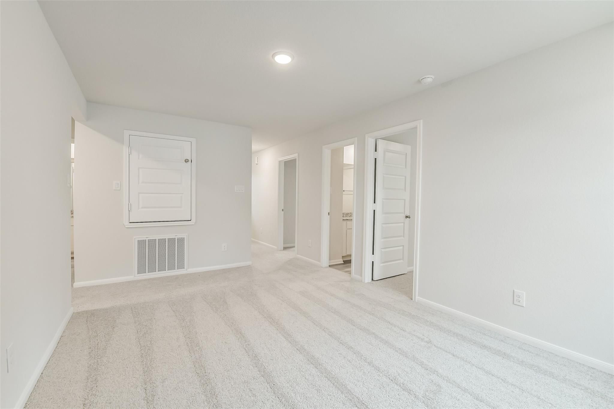 Carpeted upstairs hallway with open doors to bedrooms and baths in 5-bedroom Davidson Homes The Brazos F, Conroe, Texas
