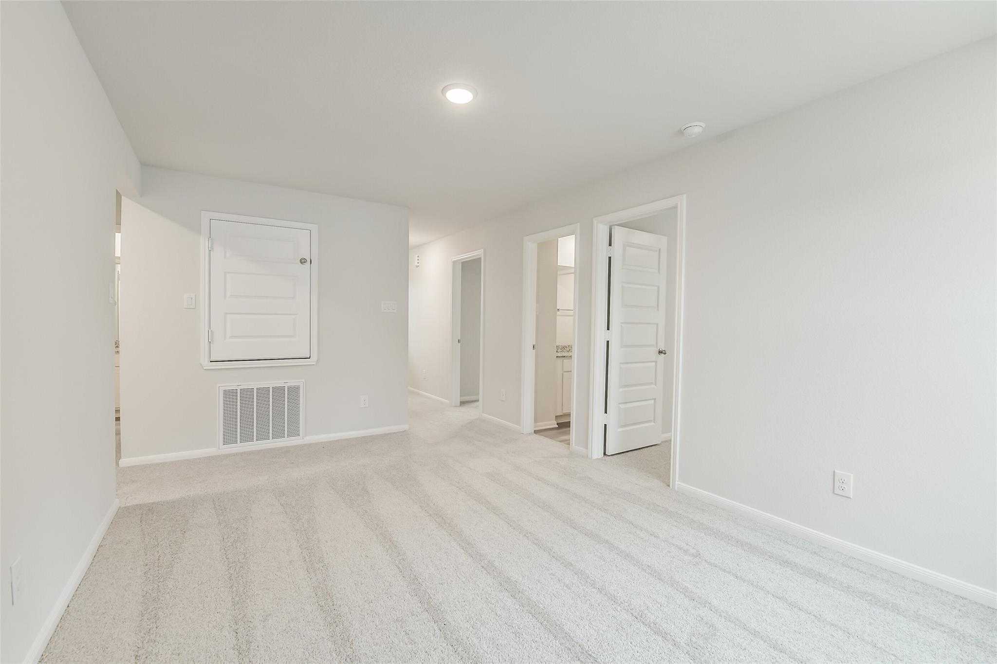 Carpeted upstairs hallway with open doors to bedrooms and baths in 5-bedroom Davidson Homes The Brazos F, Conroe, Texas