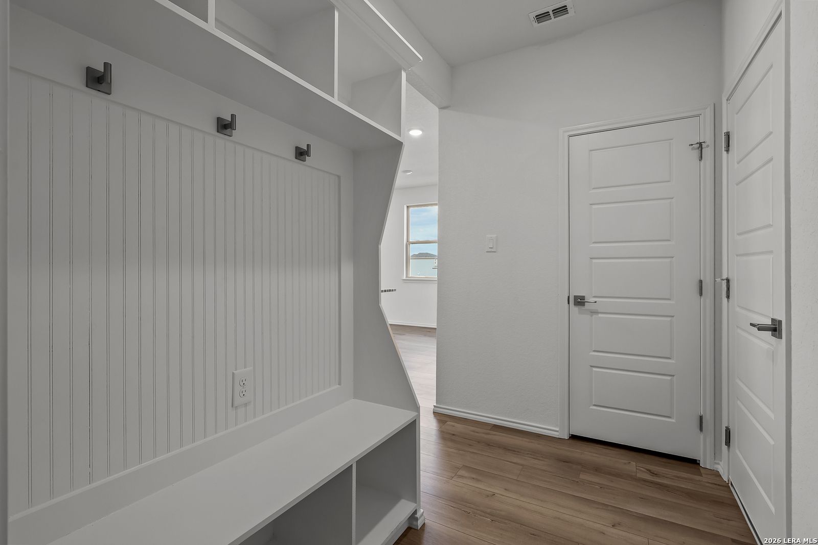 White mudroom entry with built-in bench and coat hooks in The Brazos B floor plan by Davidson Homes in Agave, San Antonio.
