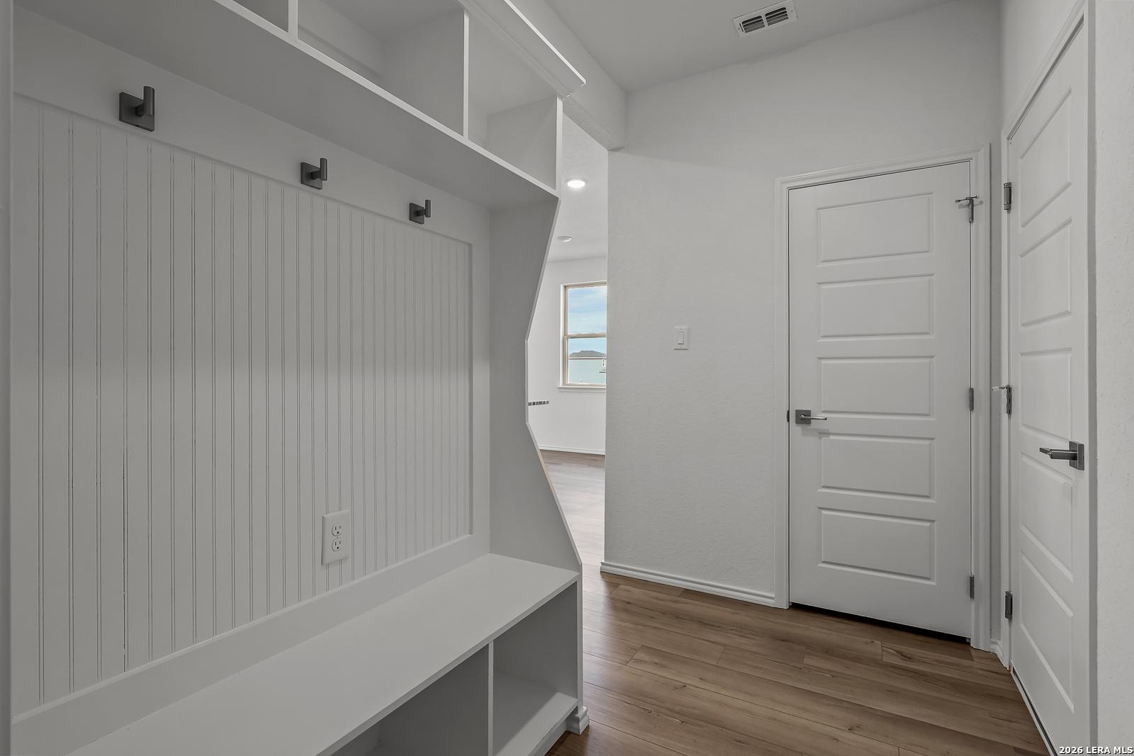 White mudroom entry with built-in bench and coat hooks in The Brazos B floor plan by Davidson Homes in Agave, San Antonio.