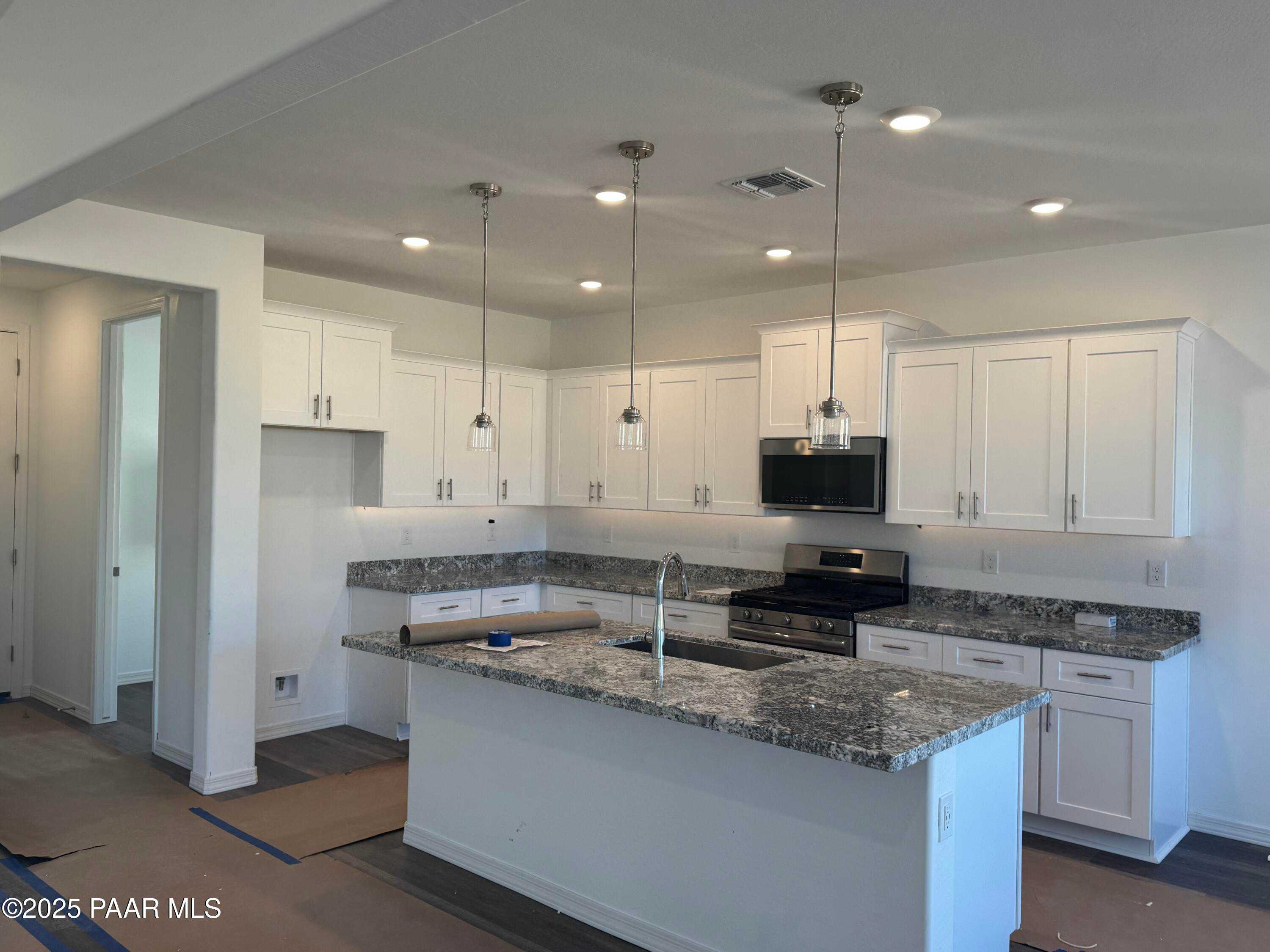 Modern white kitchen with granite island, stainless appliances, pendant lights in Davidson Homes The Summit A, Prescott AZ