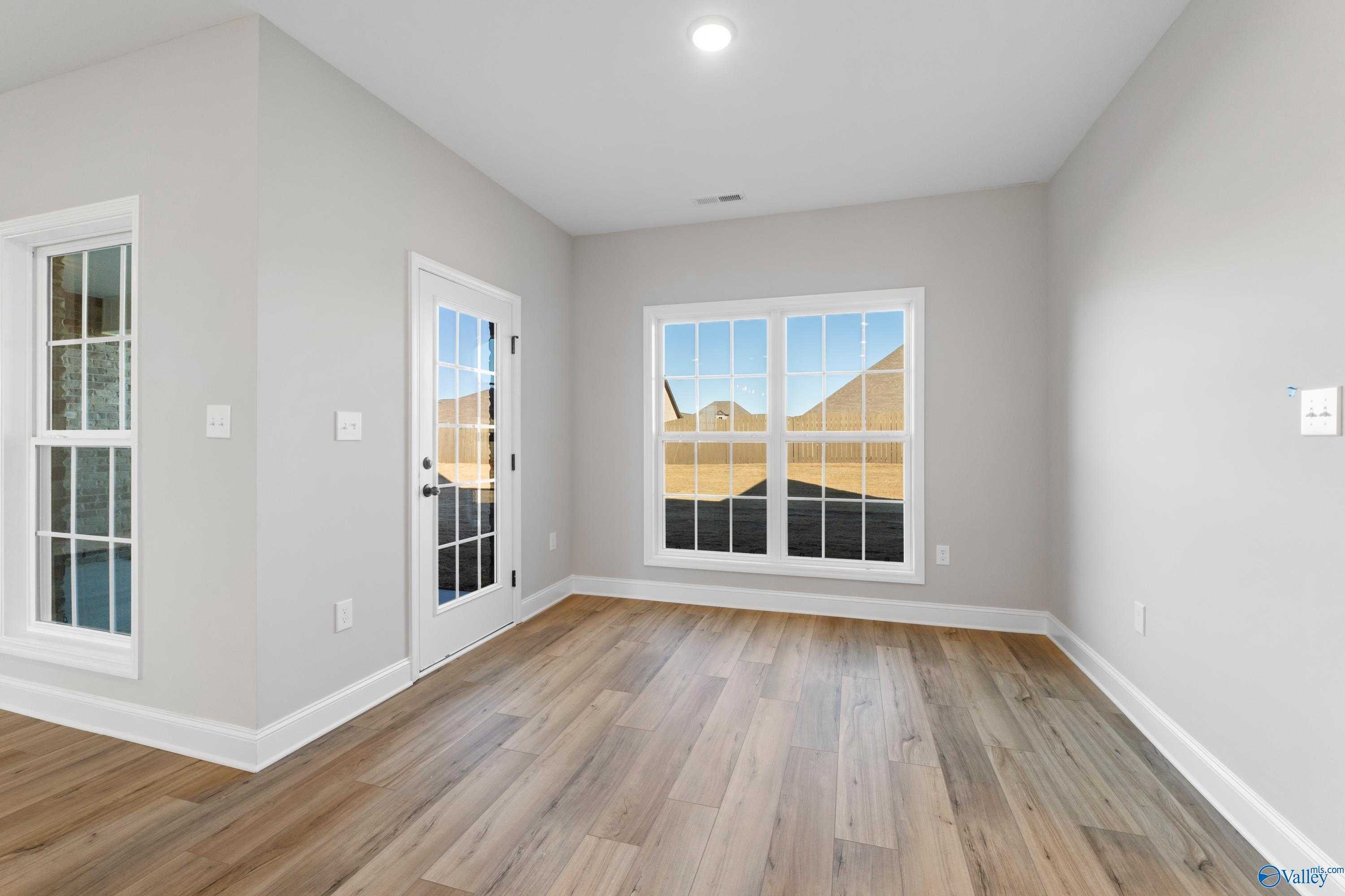 Bright flex room with light gray walls, hardwood floors, French doors, and large windows in Davidson Homes The Valencia, Meridianville, Alabama